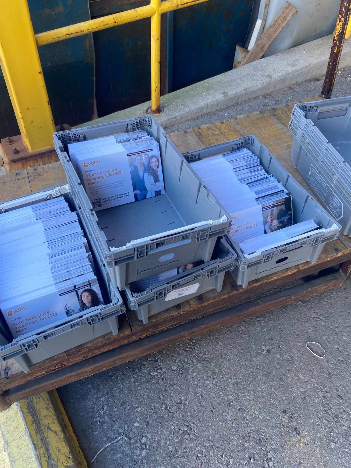 Postal trays filled with sorted, addressed postcards ready for drop-off at a mail facility