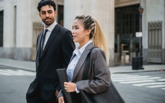 Business professionals outside an office, representing decision-makers targeted by B2B postcard campaigns.