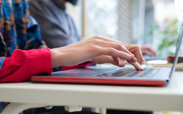 Person typing on a laptop, illustrating follow-up emails in a B2B direct mail sequence.