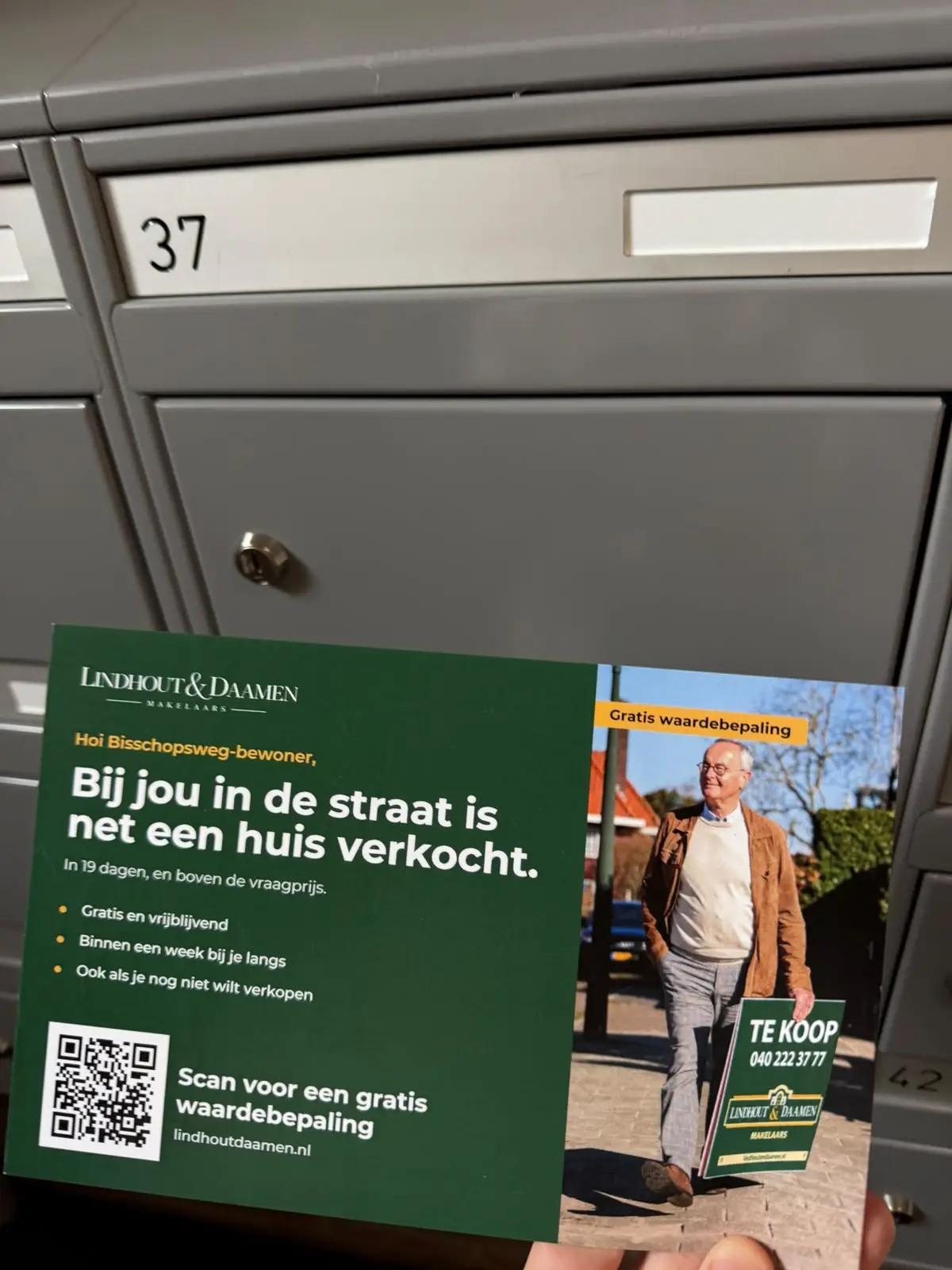 Persoonlijke makelaarskaart met de tekst 'Bij jou in de straat is net een huis verkocht' en een QR-code, voor een rij grijze brievenbussen