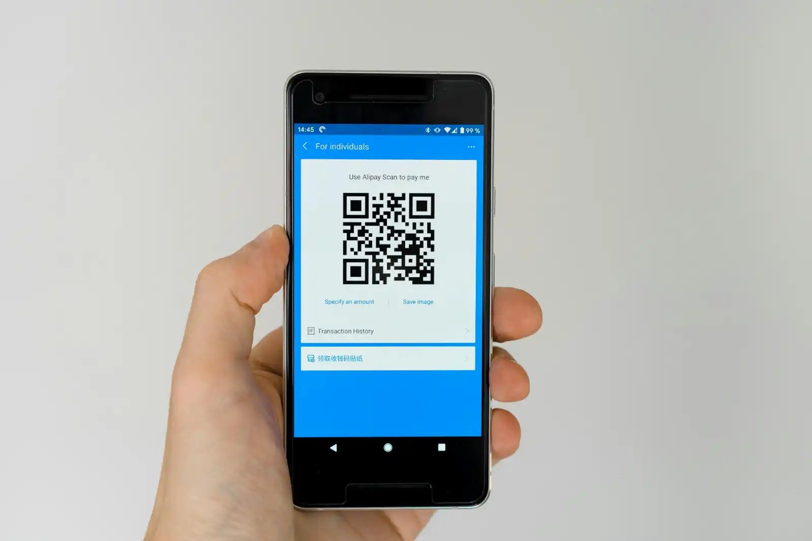 Hand holding a smartphone displaying a QR code, illustrating QR codes used in direct mail campaigns.
