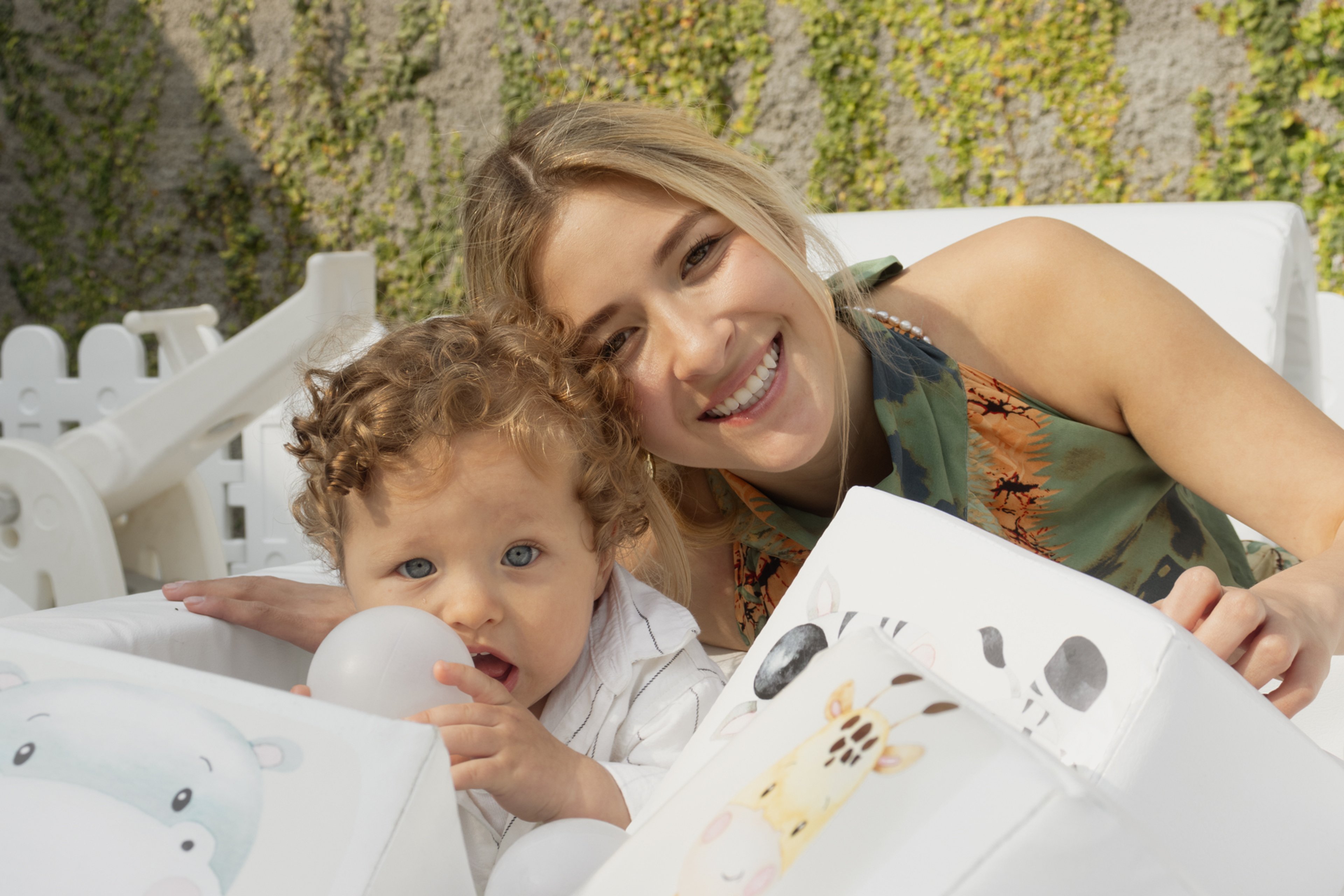 Niño y mujer sonriendo juntos entre bloques de juego blancos con ilustraciones