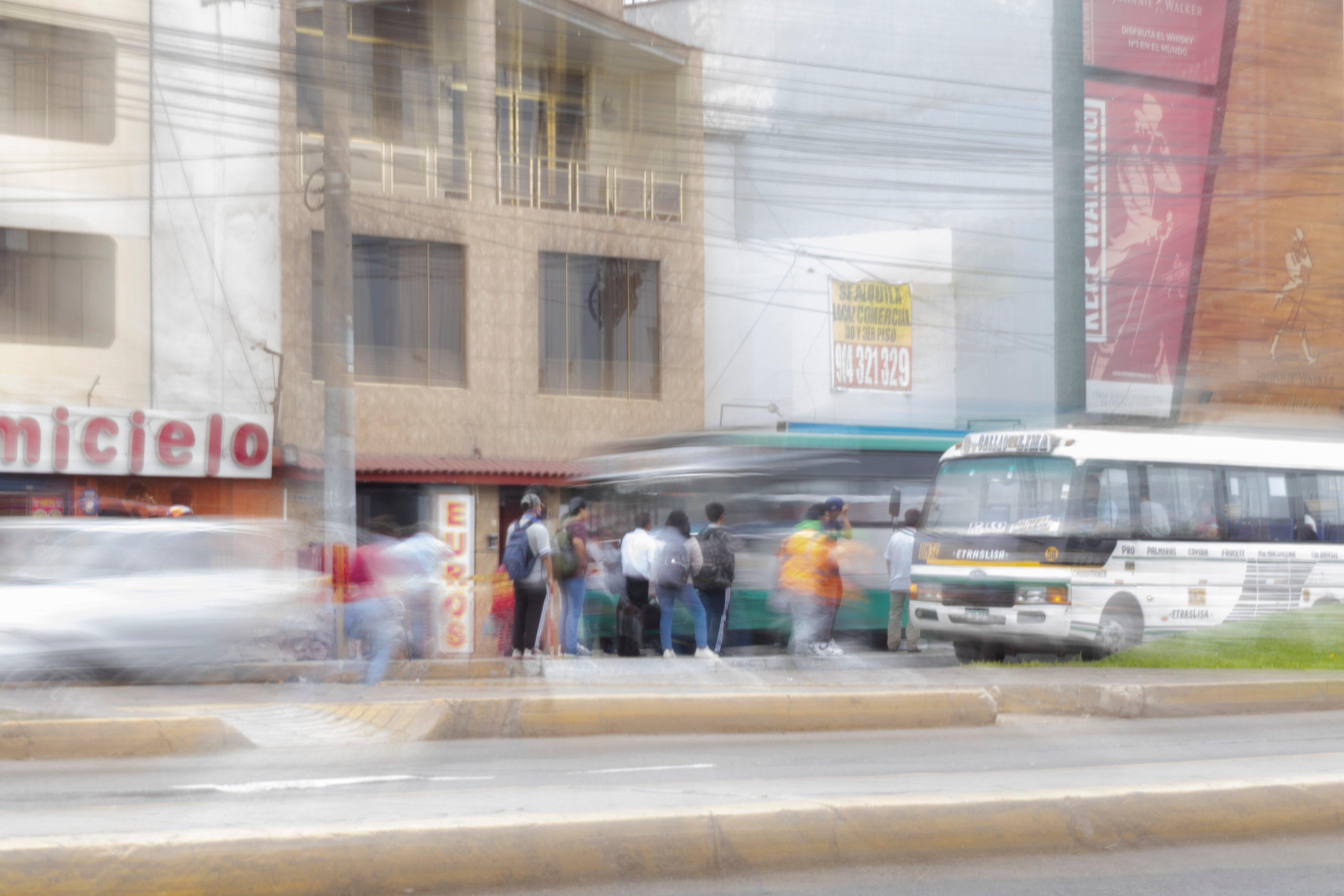 Paradero con gente subiendo a un bus mientras los vehículos pasan rápidamente