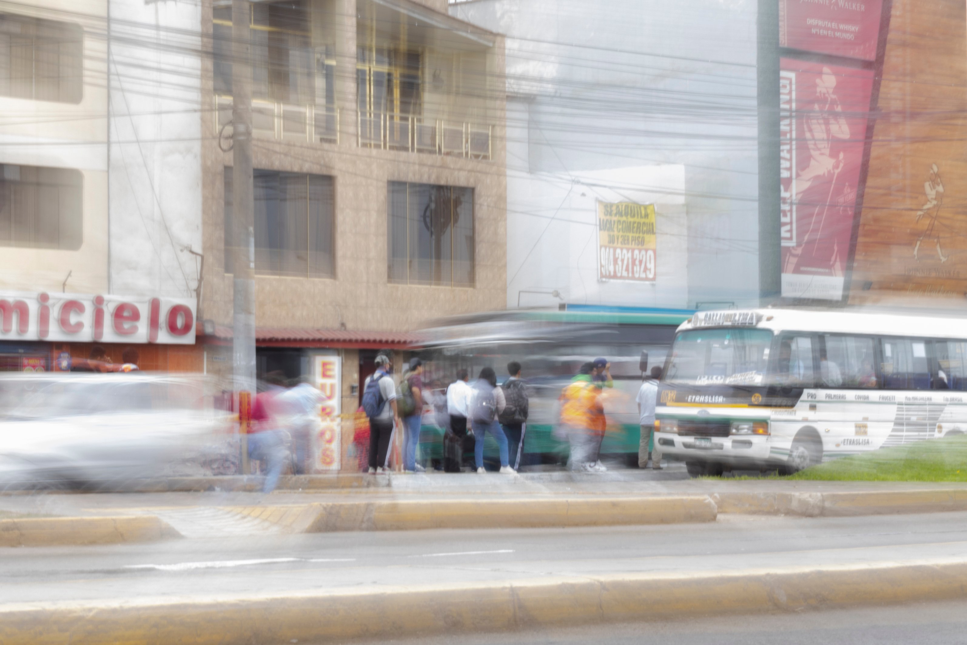 Paradero con gente subiendo a un bus mientras los vehículos pasan rápidamente