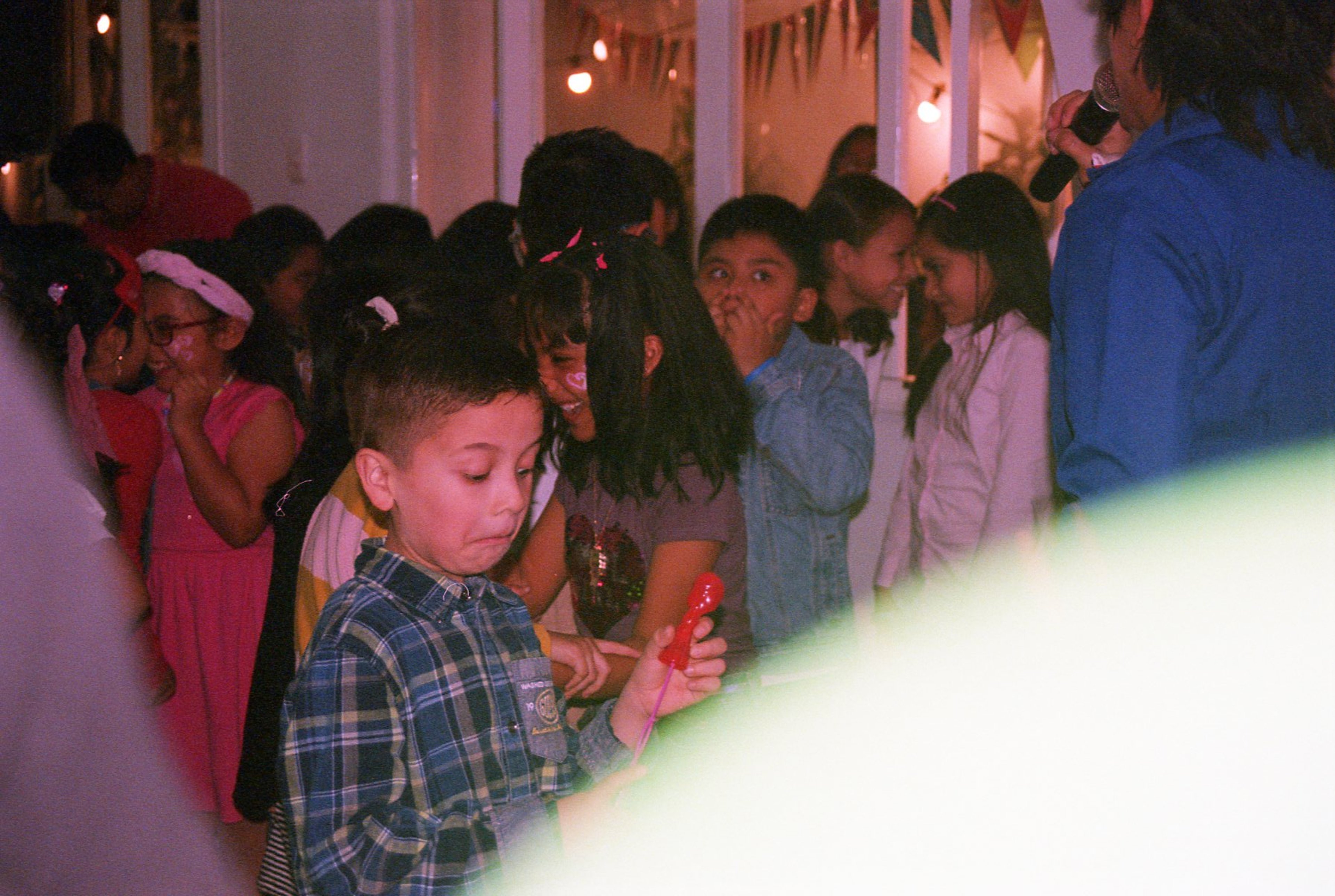 Niño en una fiesta infantil mirando un juguete mientras otros niños conversan al fondo