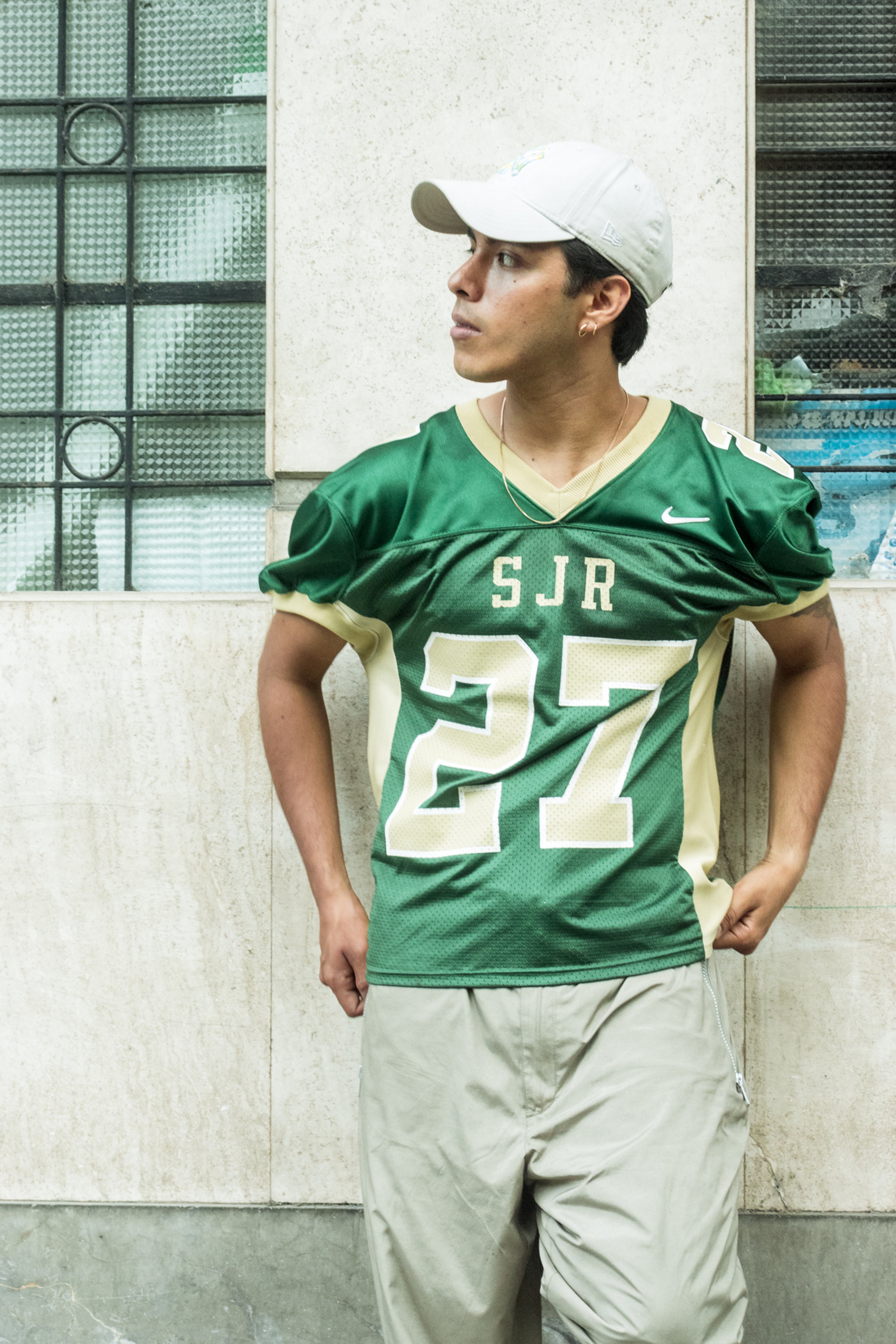 Retrato urbano de un joven con camiseta deportiva verde número 27