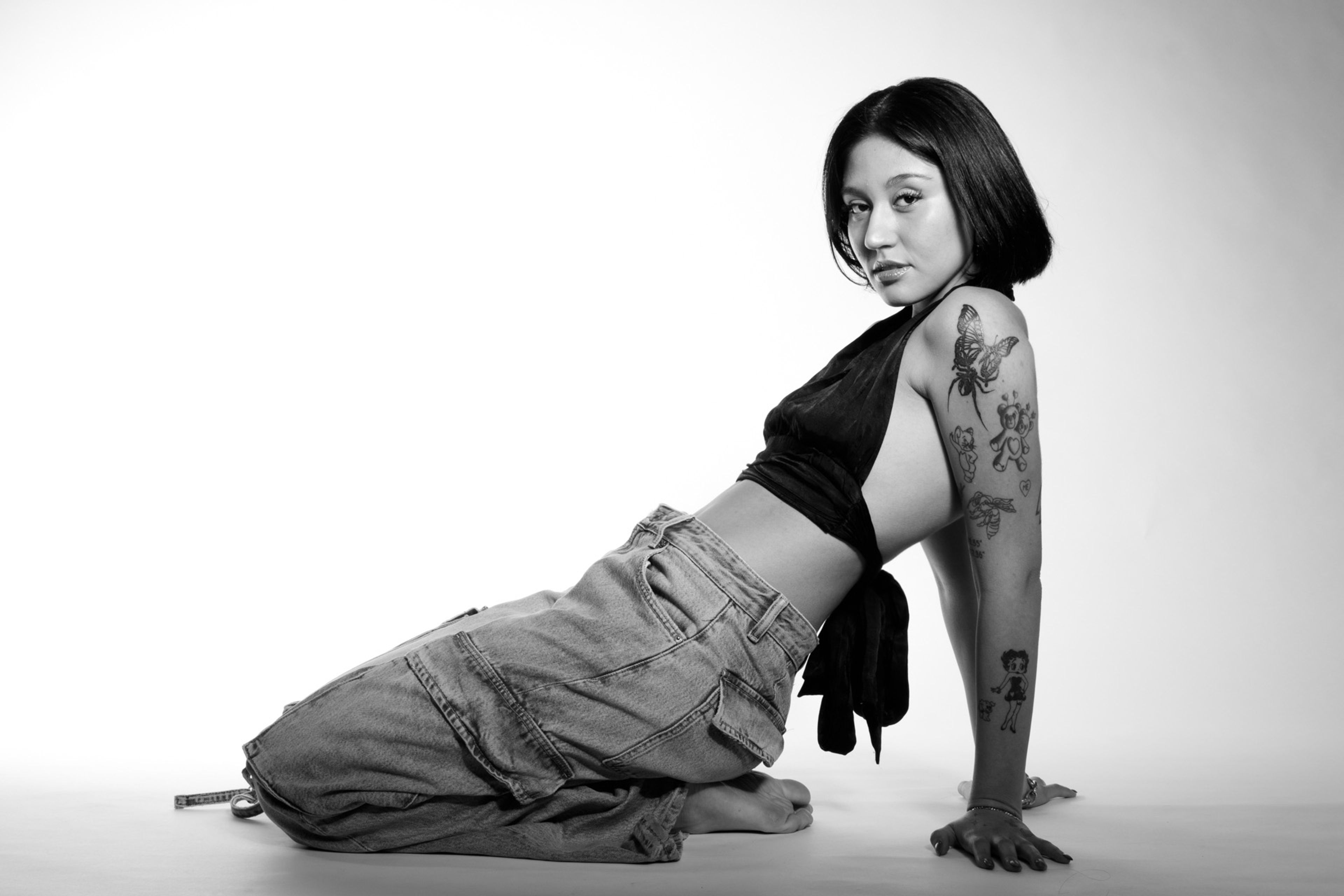 Retrato en estudio en blanco y negro de una modelo posando sentada en el piso