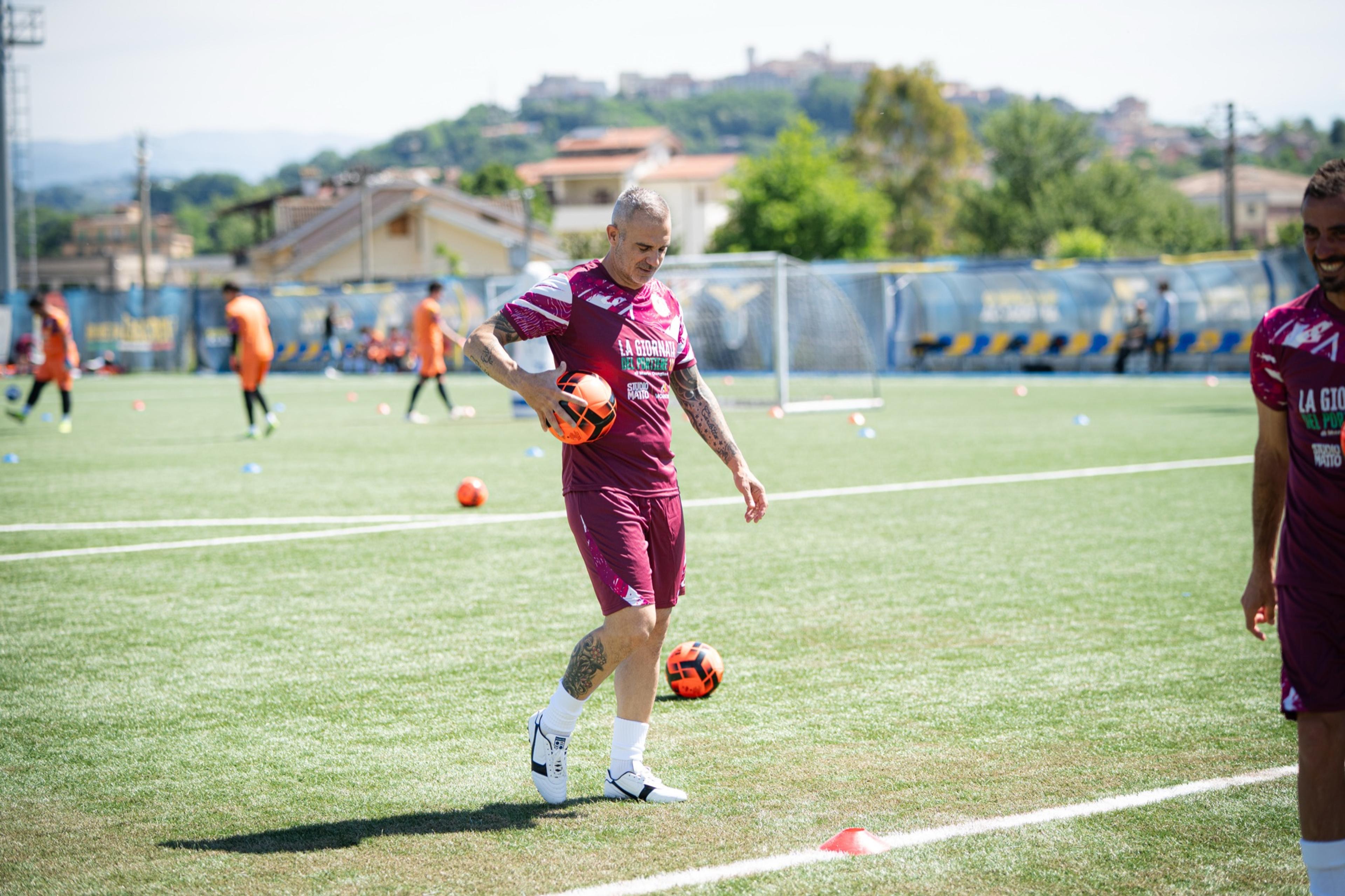 Un preparatore palleggia sul campo, sullo sfondo i portieri