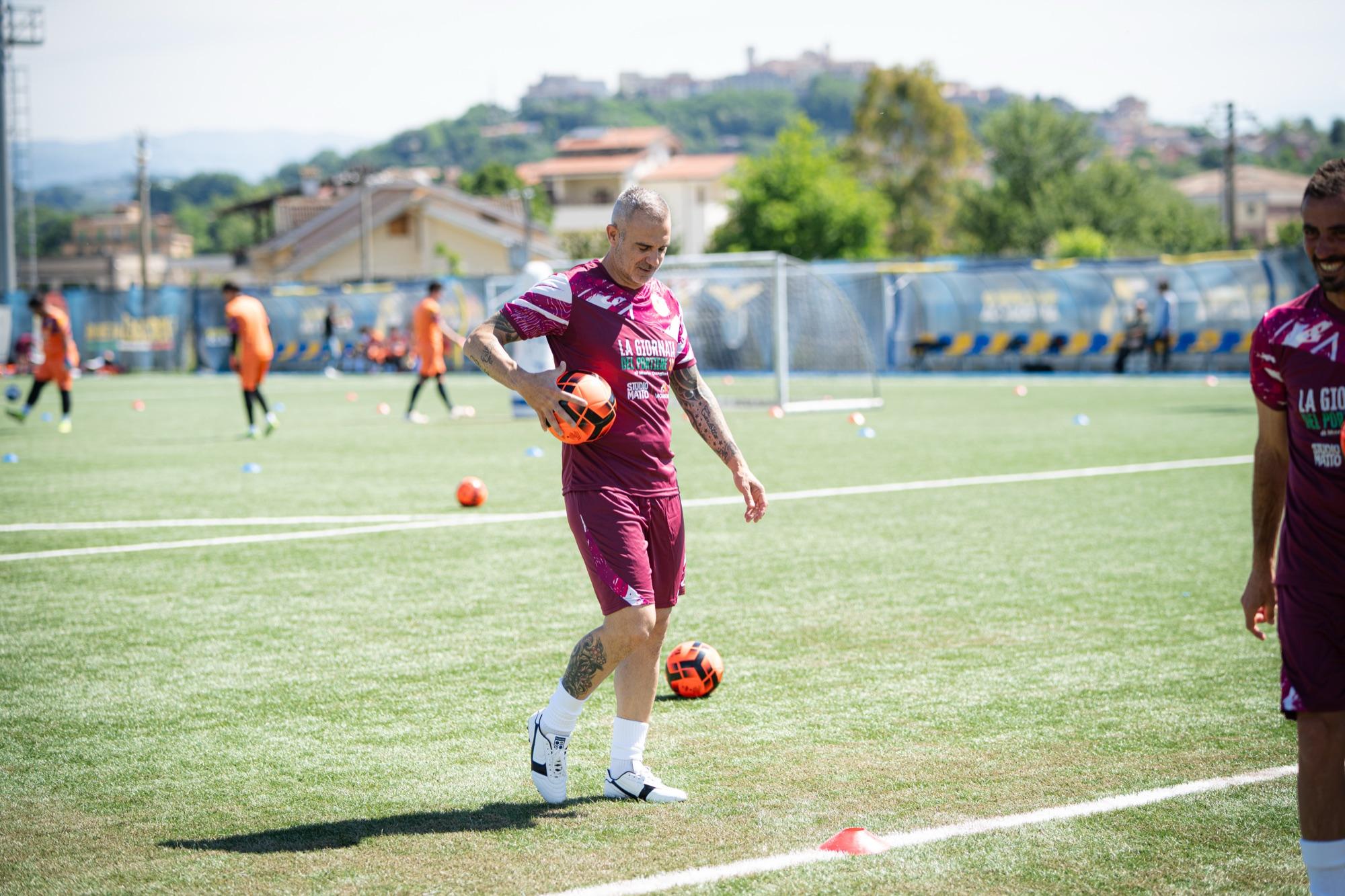 Un preparatore palleggia sul campo, sullo sfondo i portieri