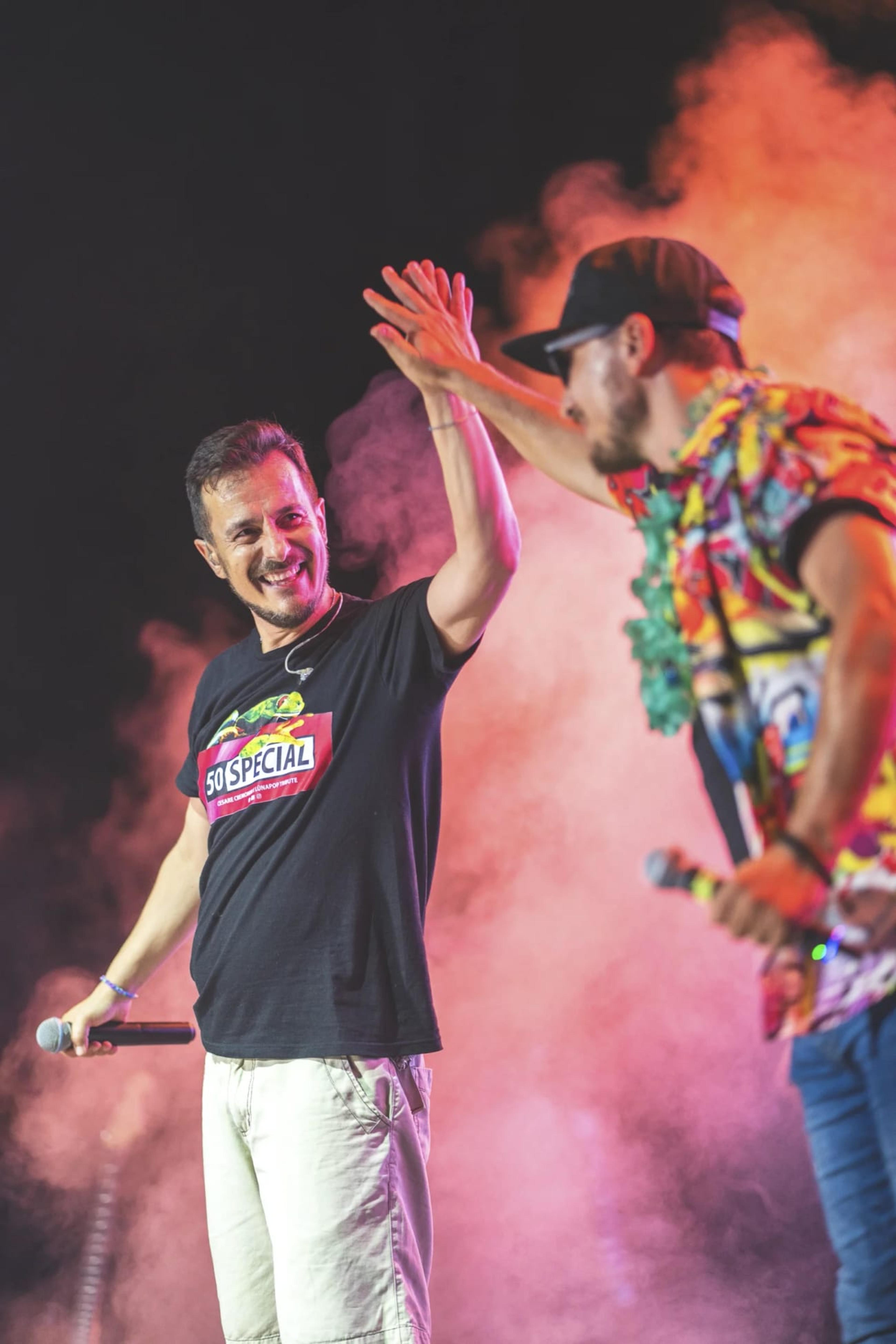 Due cantanti della band 883 Come Max sul palco, tra fumo e luci