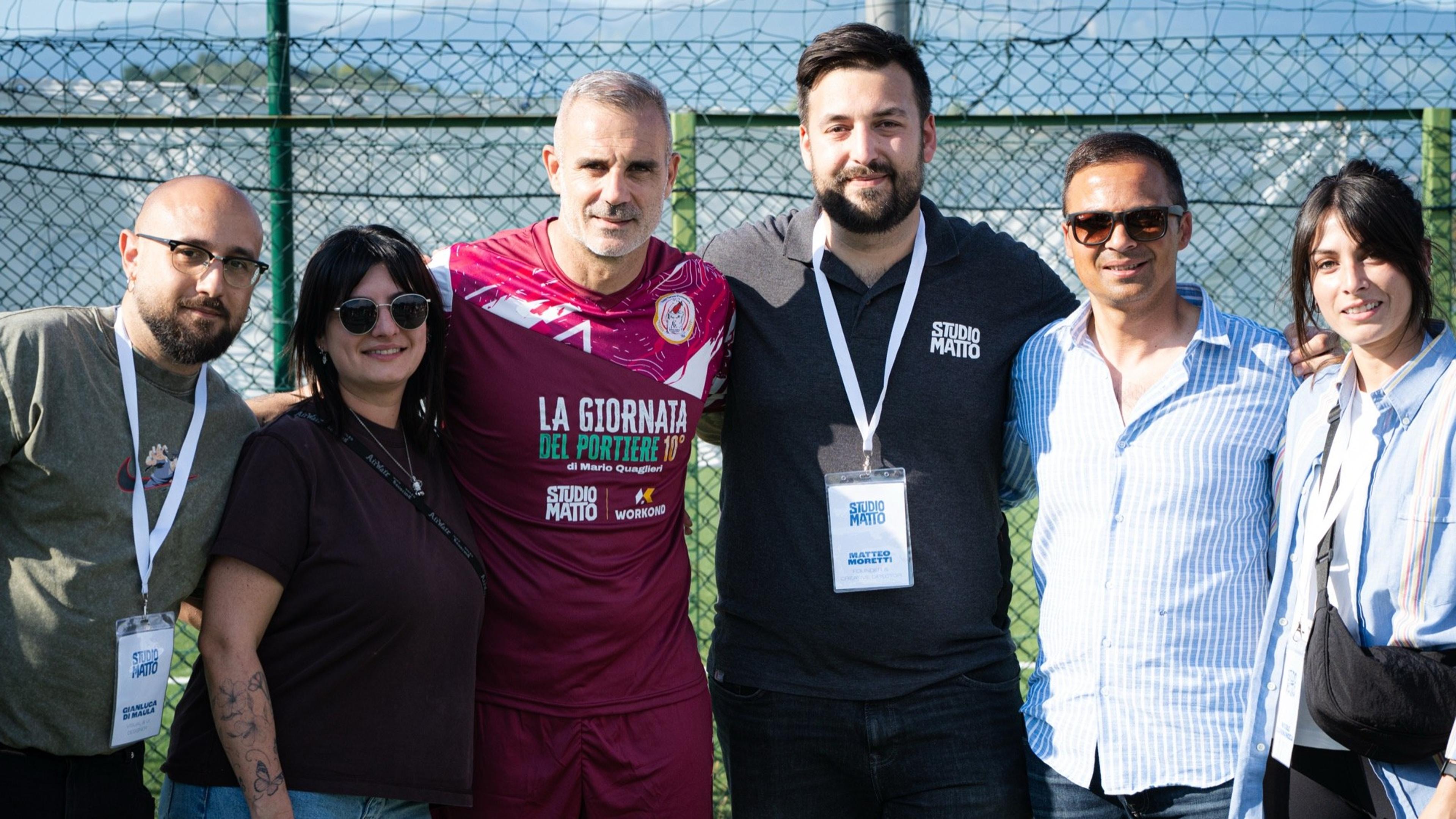 Foto di gruppo dello staff con il team di Studio Matto a bordo campo