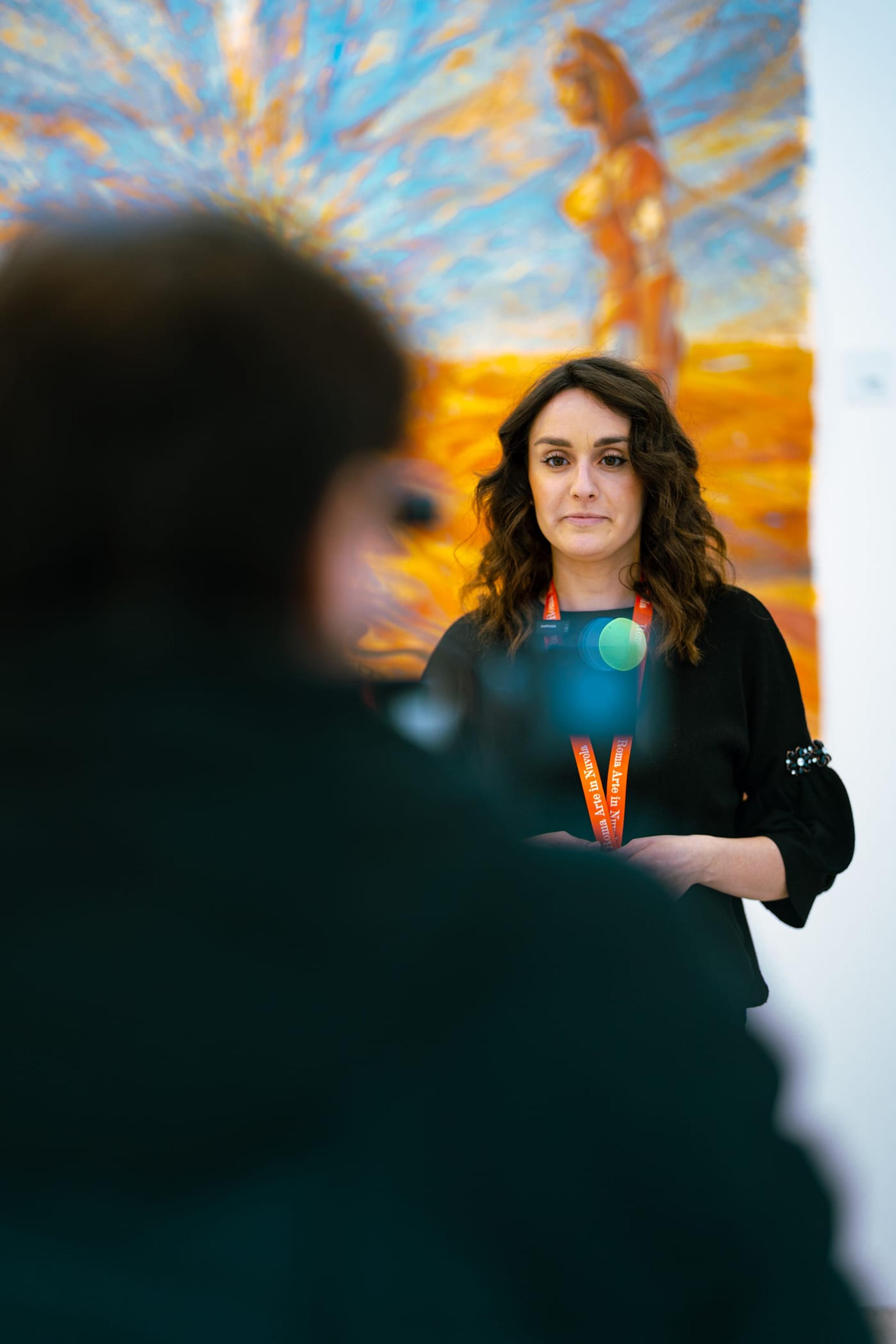 Una visitatrice con il badge, davanti a un dipinto