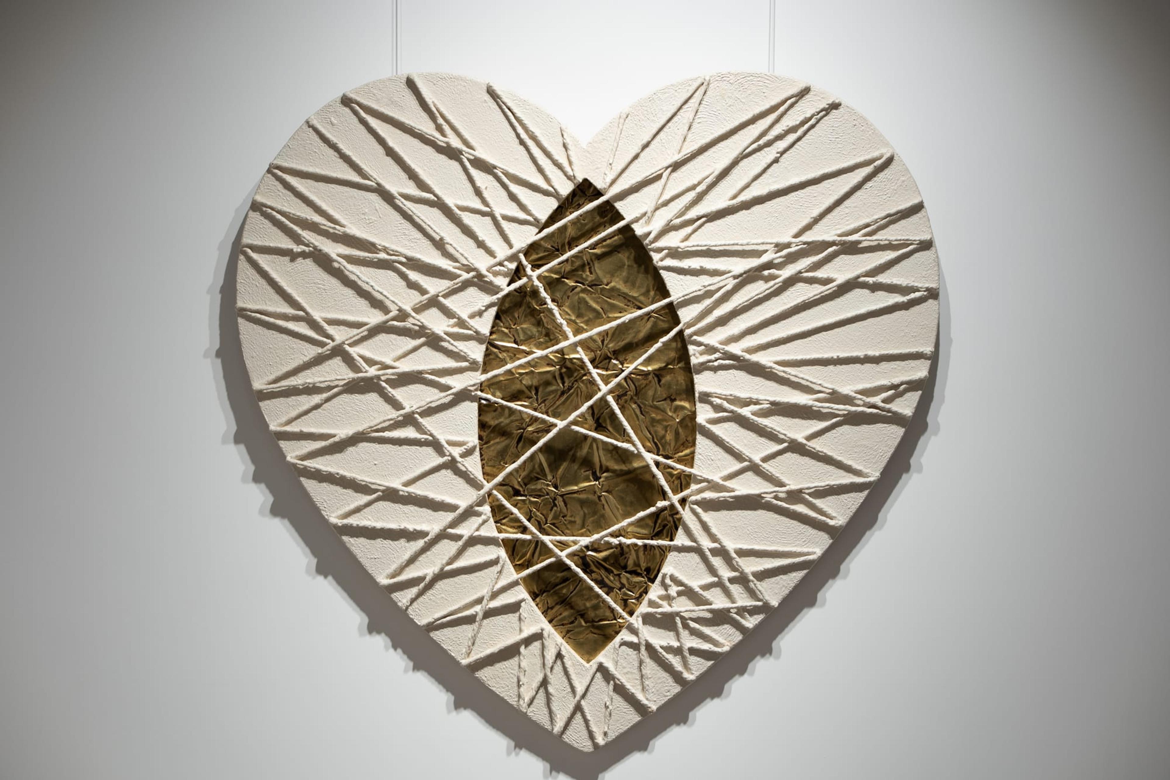 Un cuore bianco in rilievo, attraversato da fili