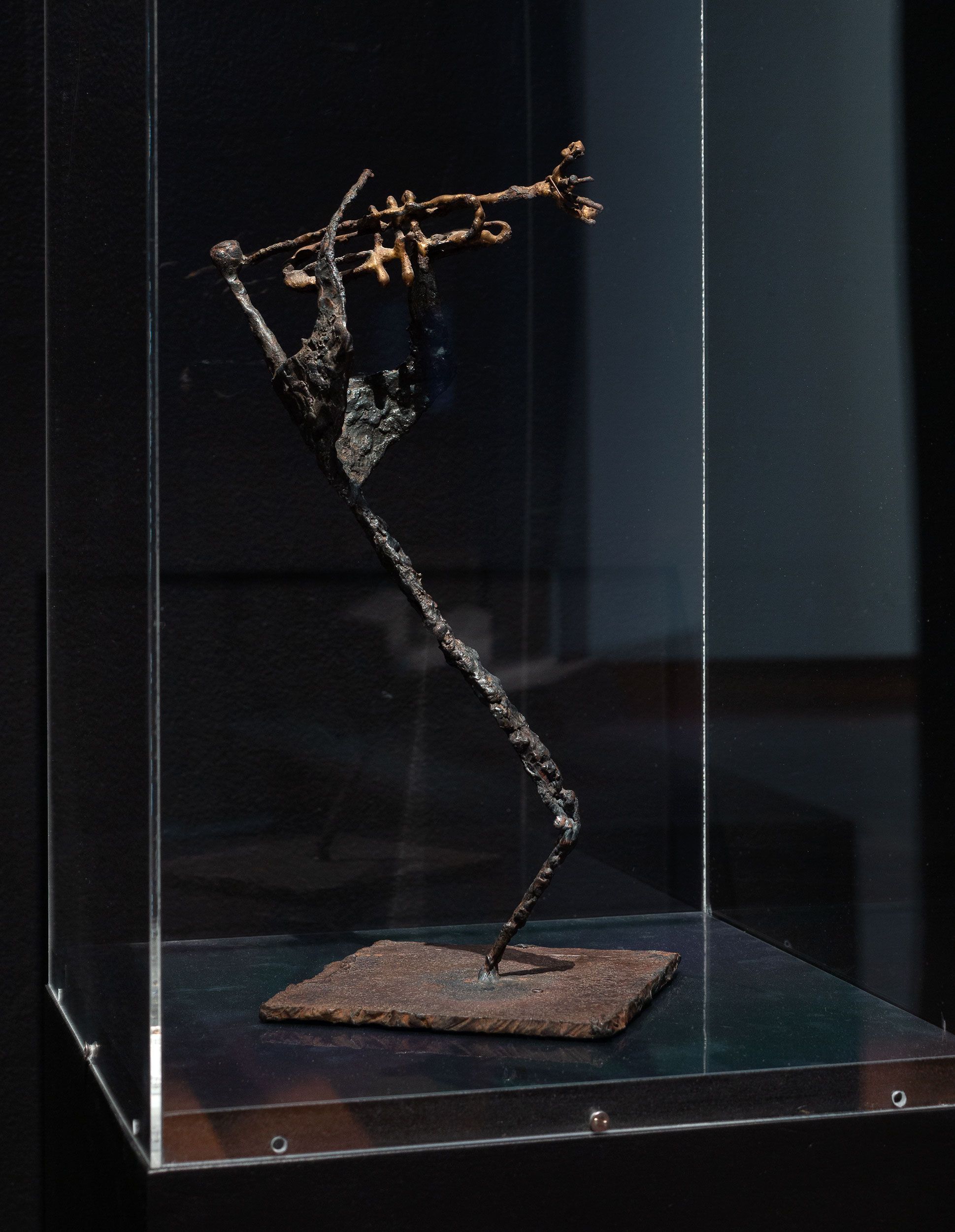 A photograph of a bronze sculpture of stylised stick figure playing a saxophone