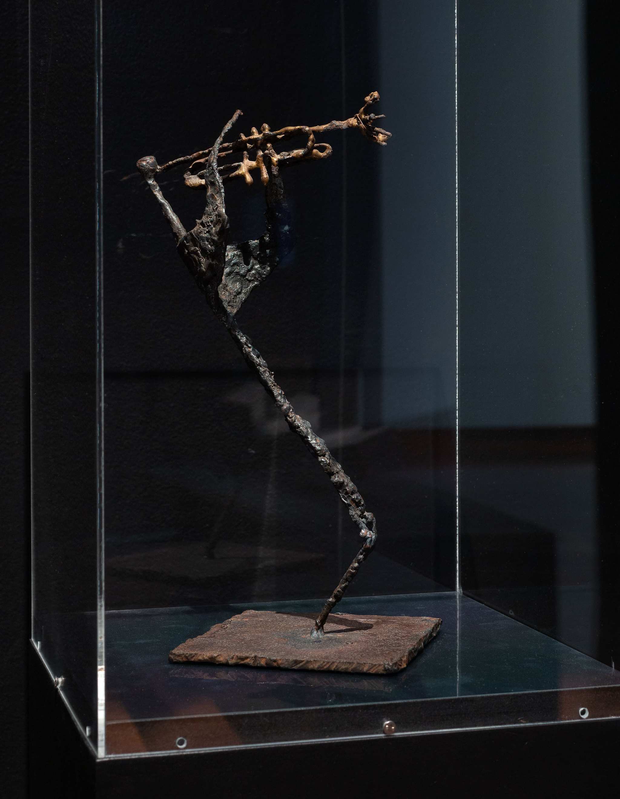 A photograph of a bronze sculpture of stylised stick figure playing a saxophone