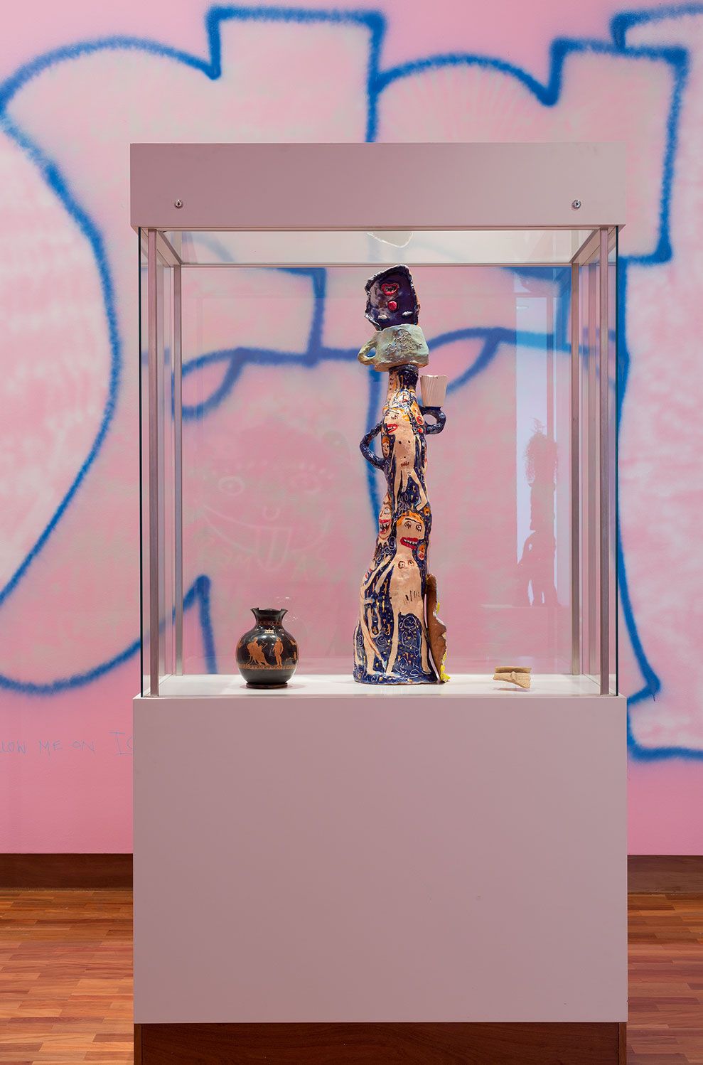 A sculpture of a creature holding a cup in a glass plinth