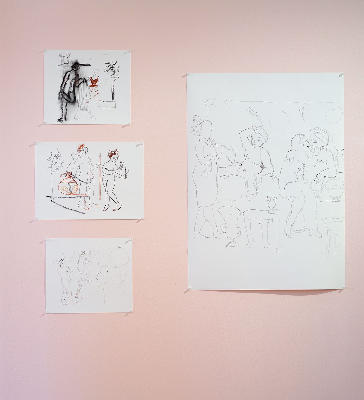 A photo of four sketches of human figures pinned on the pink wall