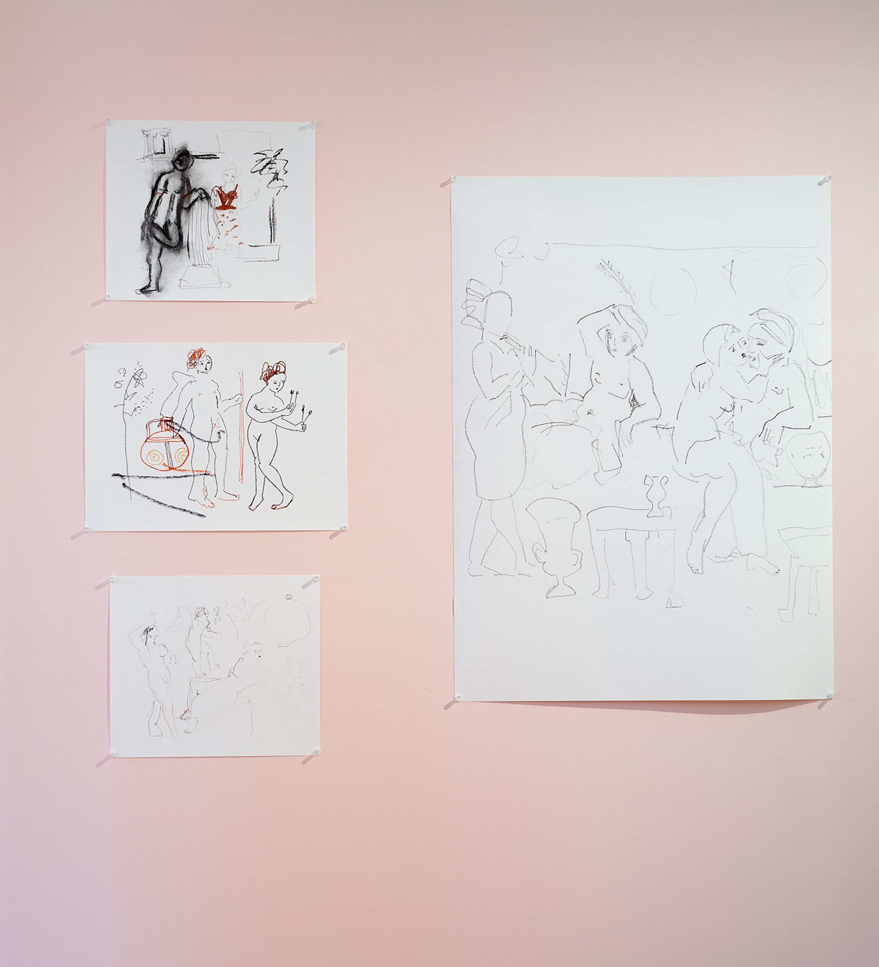 A photo of four sketches of human figures pinned on the pink wall