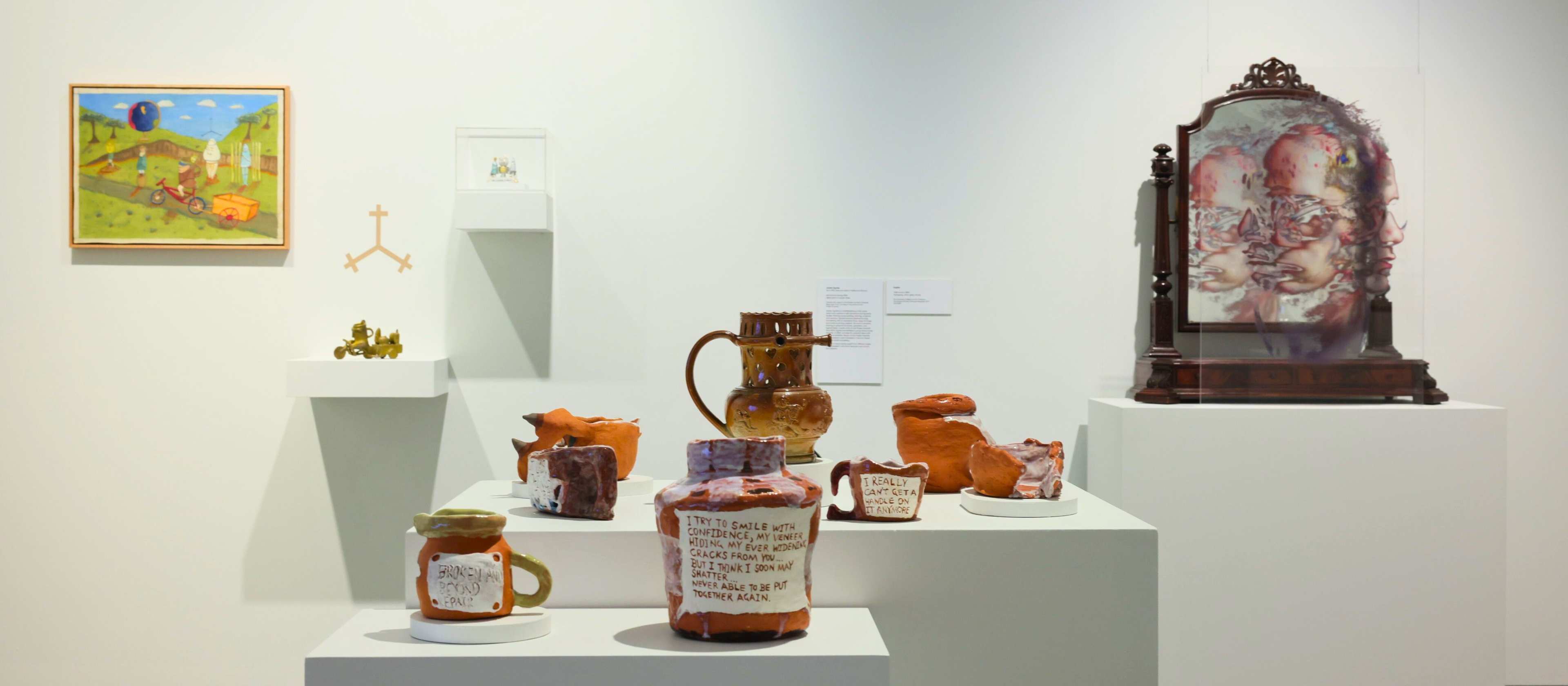 Pottery display on plinth, painting and mirrored installation in gallery.