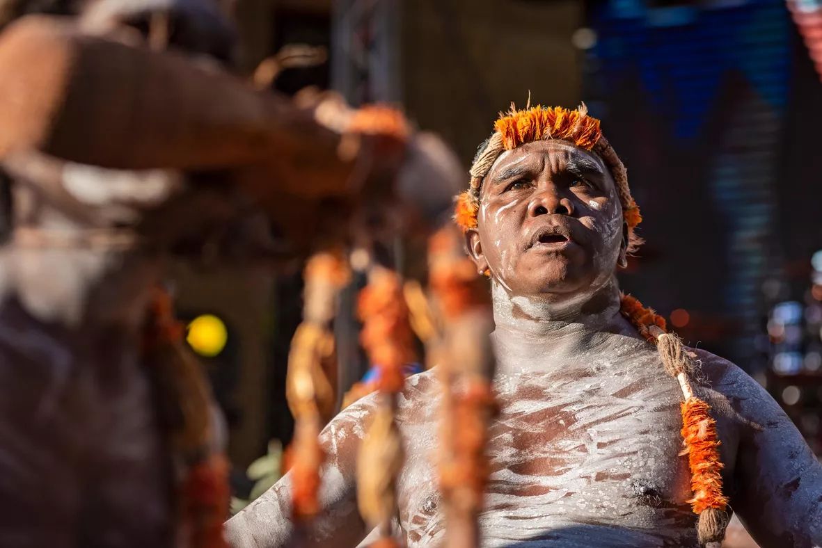 Yinimala Gumana in body paint and traditional headwear, looking up during a performance.