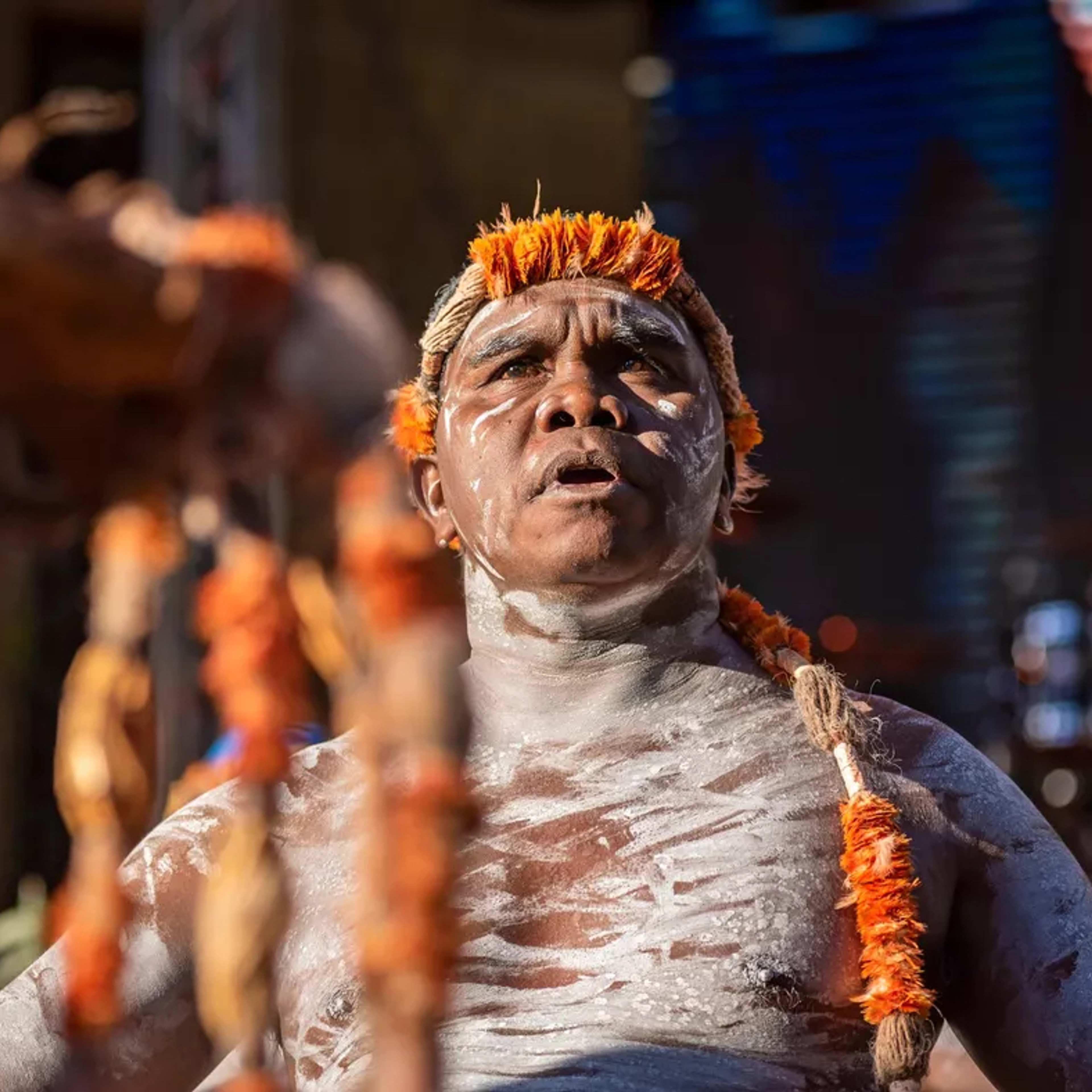 Yinimala Gumana in body paint and traditional headwear, looking up during a performance.