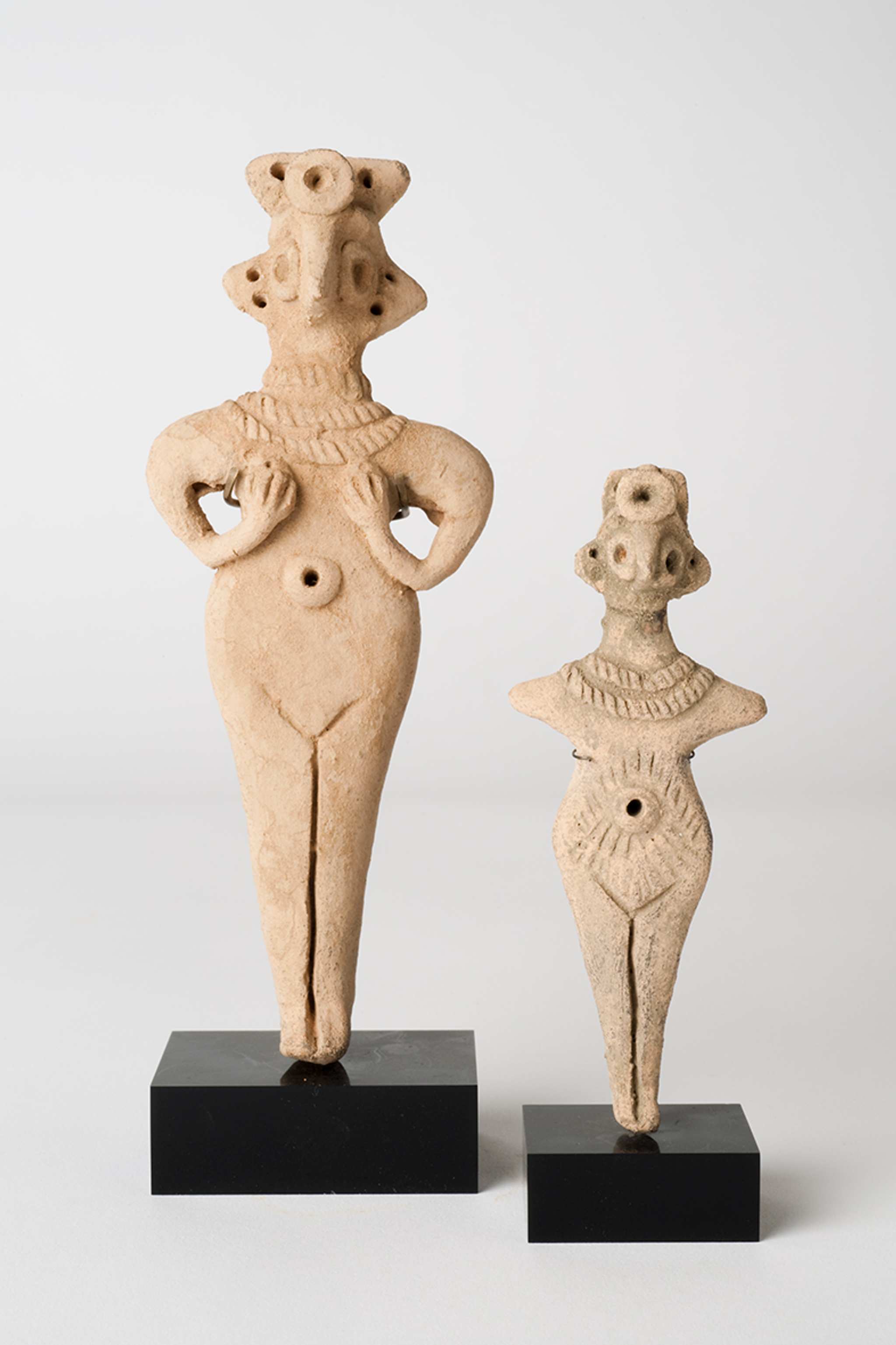 Two terracotta figurines of semi-abstracted human shapes in a row