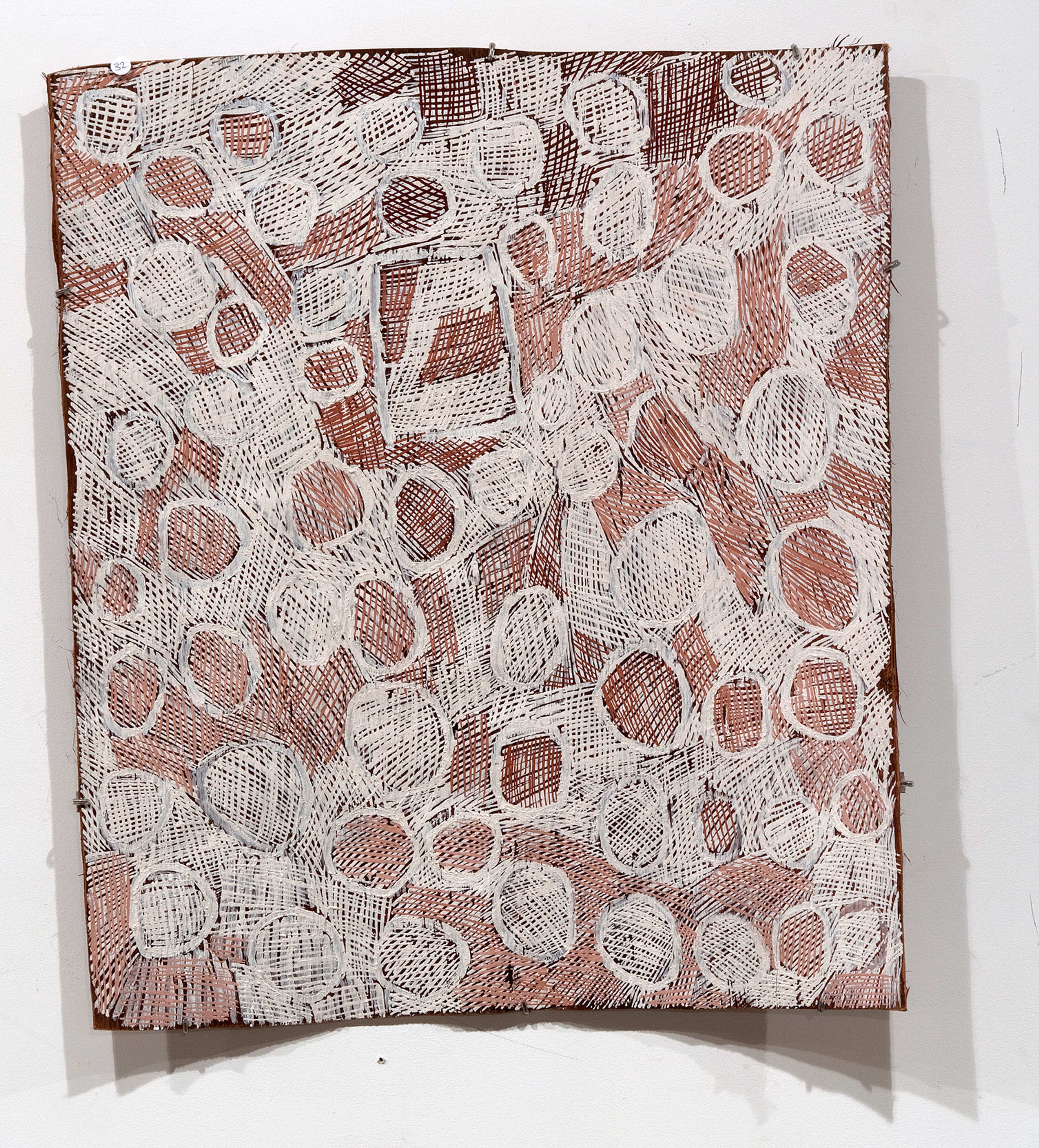 A bark paintings with cross-hatched ovals filling warm brown cross-hatched background, one square shape hiding between the ovals.