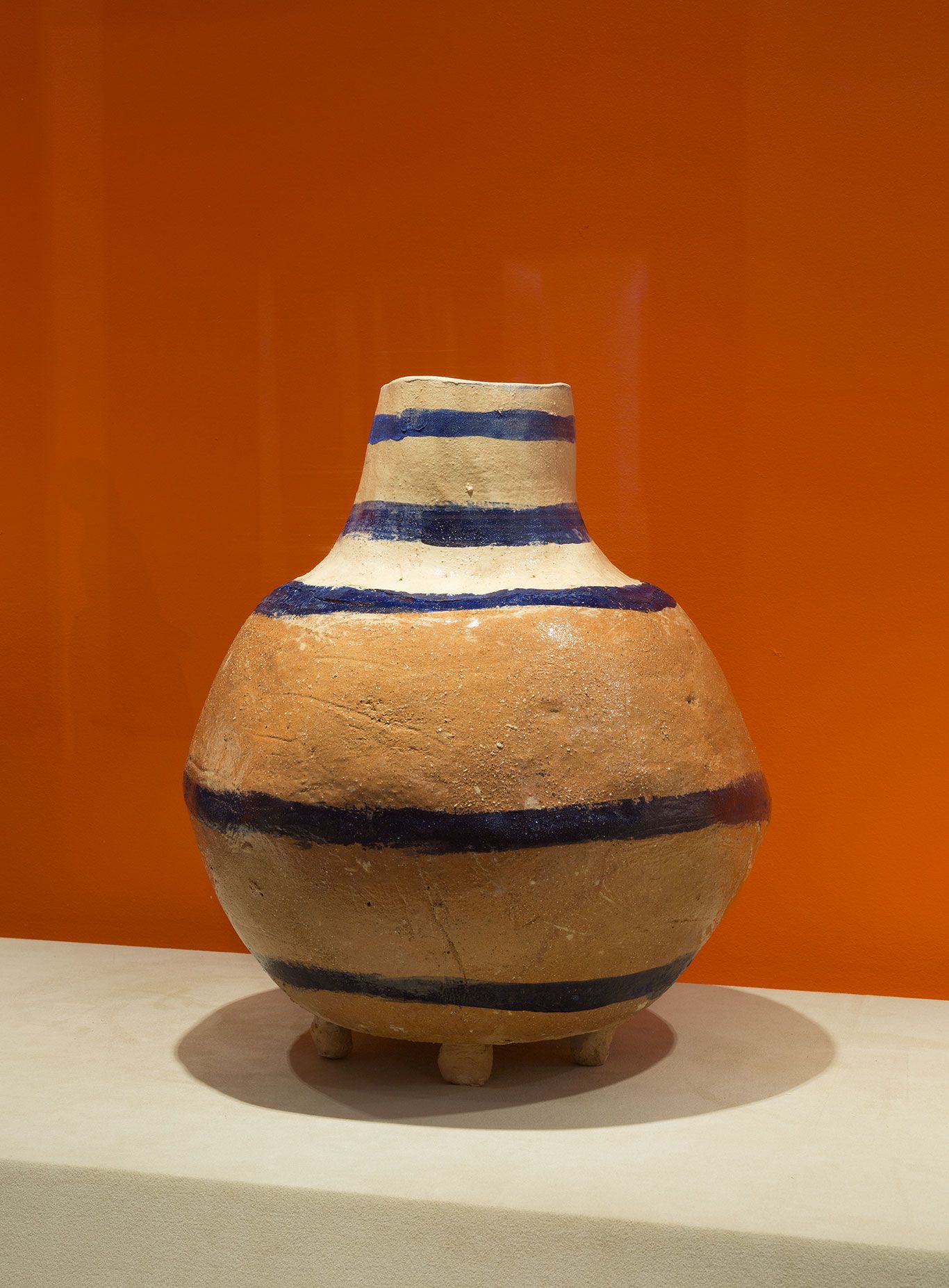 A photograph of a contemporary handmade ceramic vessels with rotund body painted with black and ground stripes