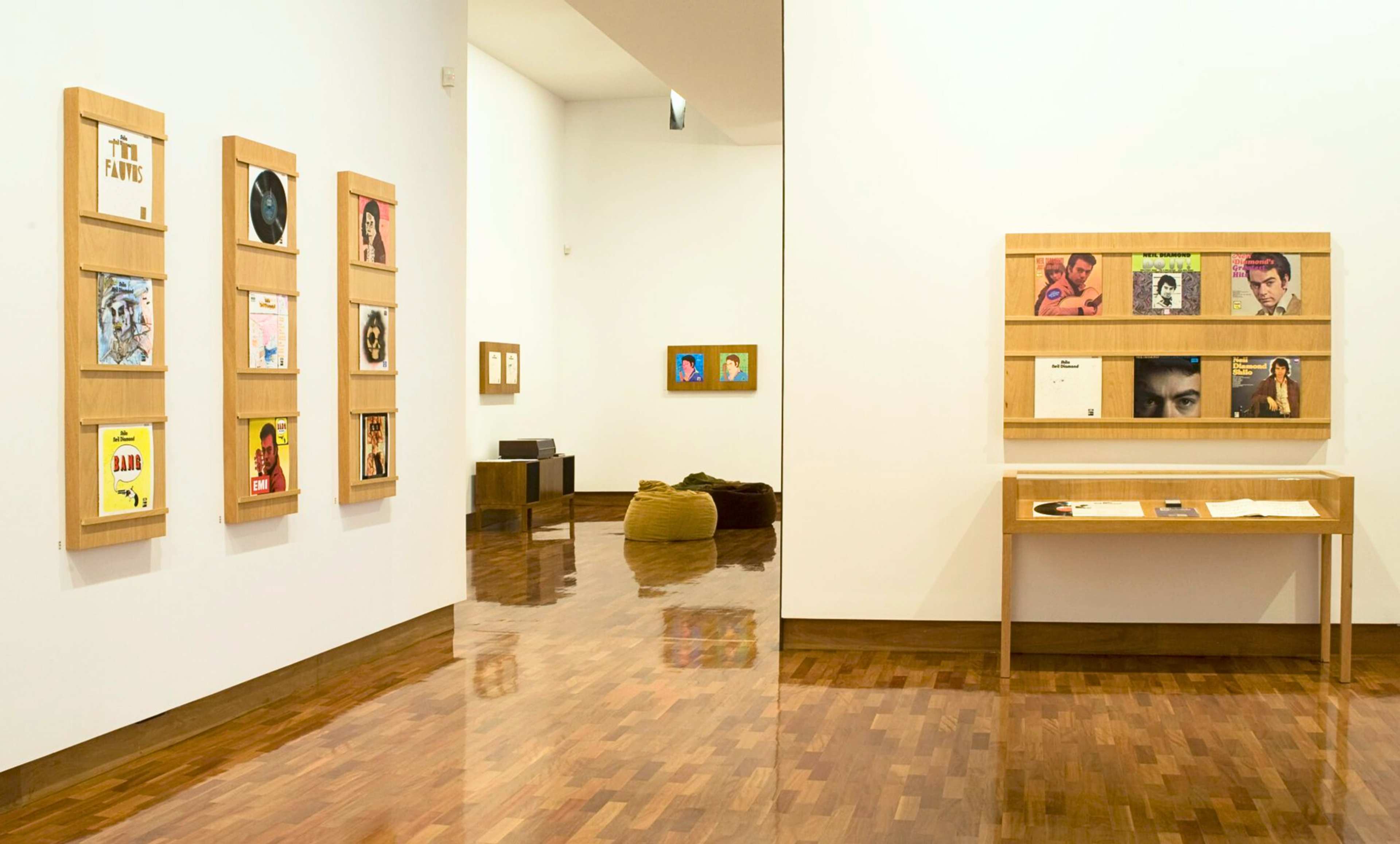 A photograph of a gallery featuring record sleeves in display shelves and vitrines
