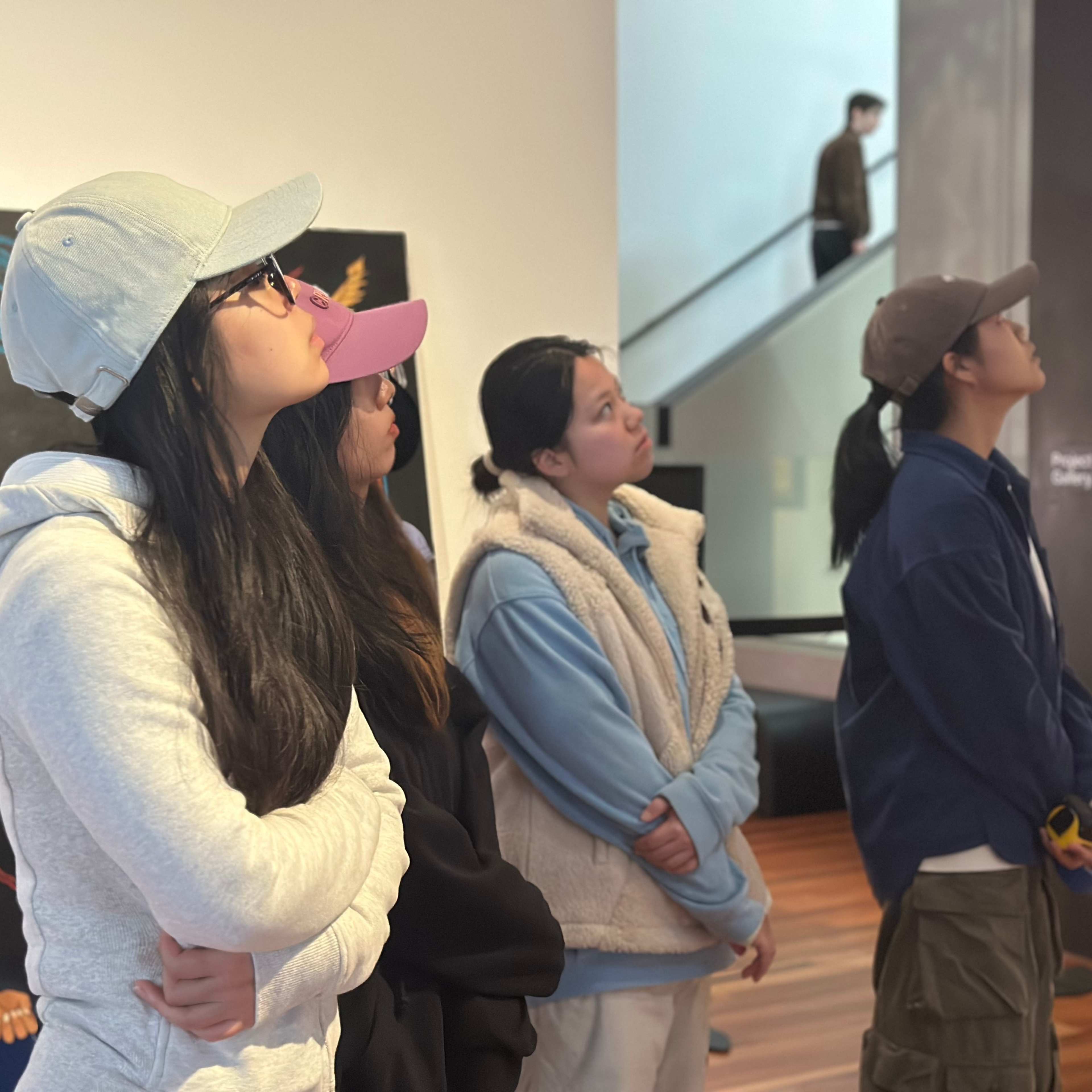 Four students looking up in a gallery space.