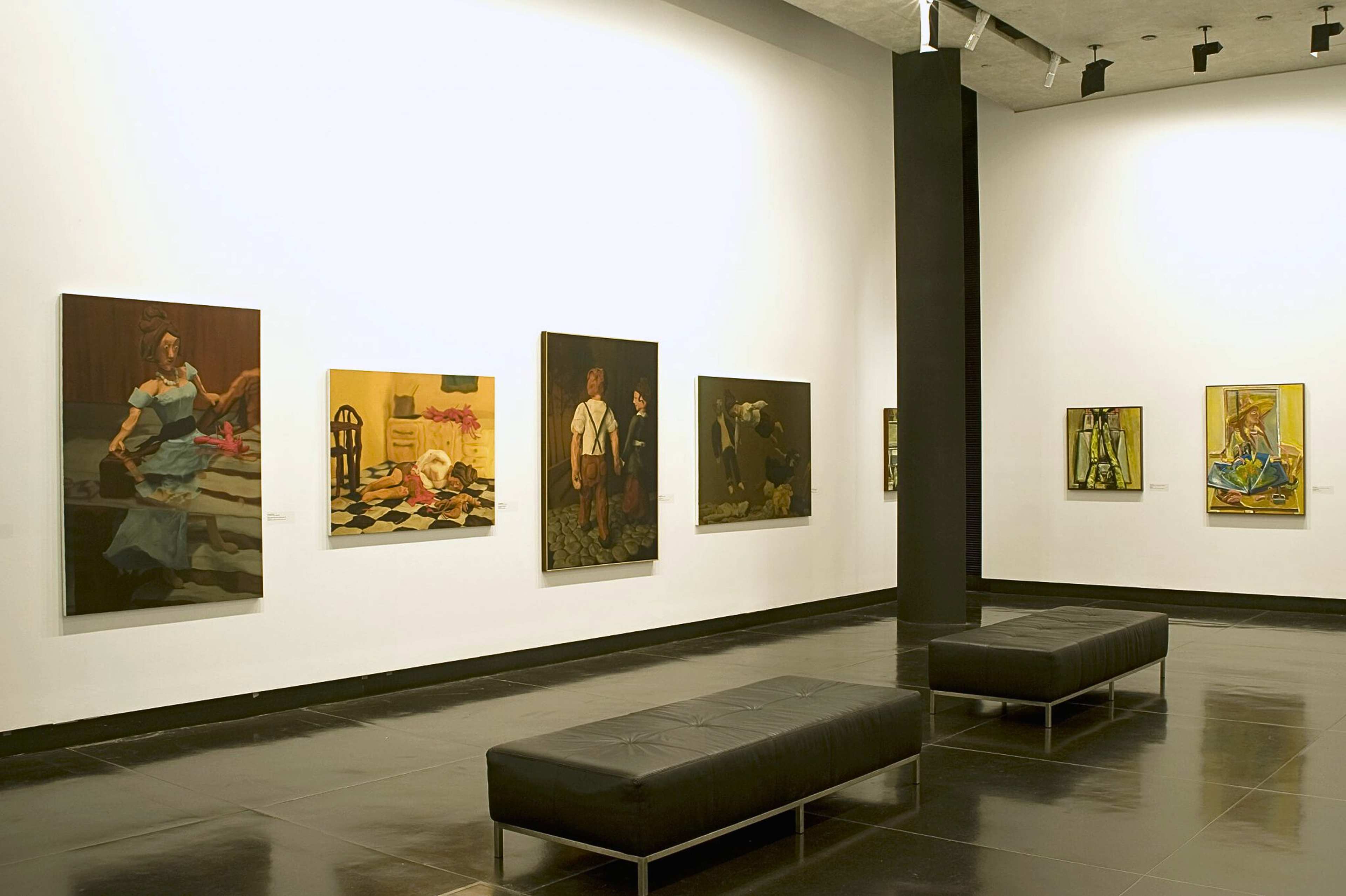 A photograph of a gallery with paintings featuring various figures hanging on the walls