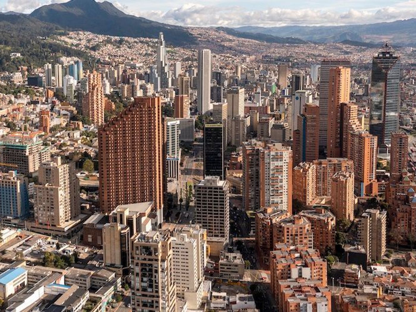 Panoramic view of Bogotá with high-rise buildings and mountains in the distance.