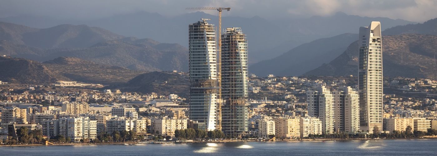 Limassol waterfront skyline with high-rise buildings and mountains behind the city.