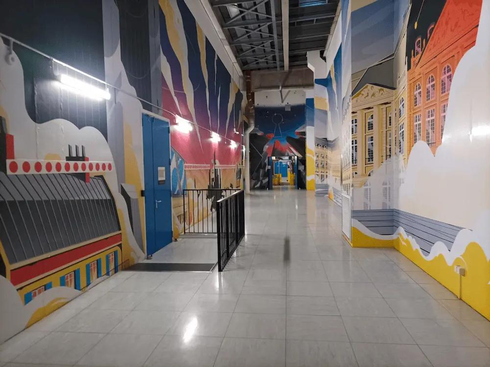 Data centre corridor with colourful wall murals and overhead cable trays.