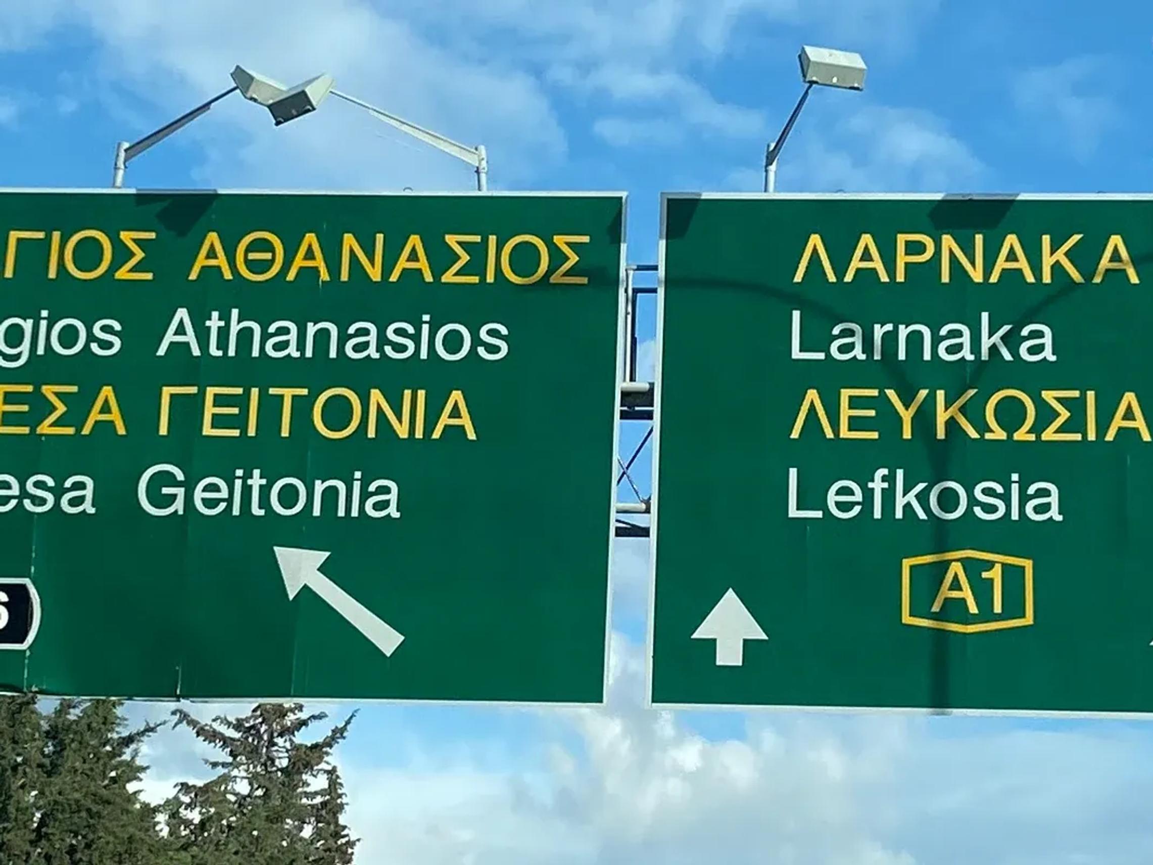 Road signs in Cyprus showing directions to Agios Athanasios, Mesa Geitonia, Larnaka and Lefkosia.