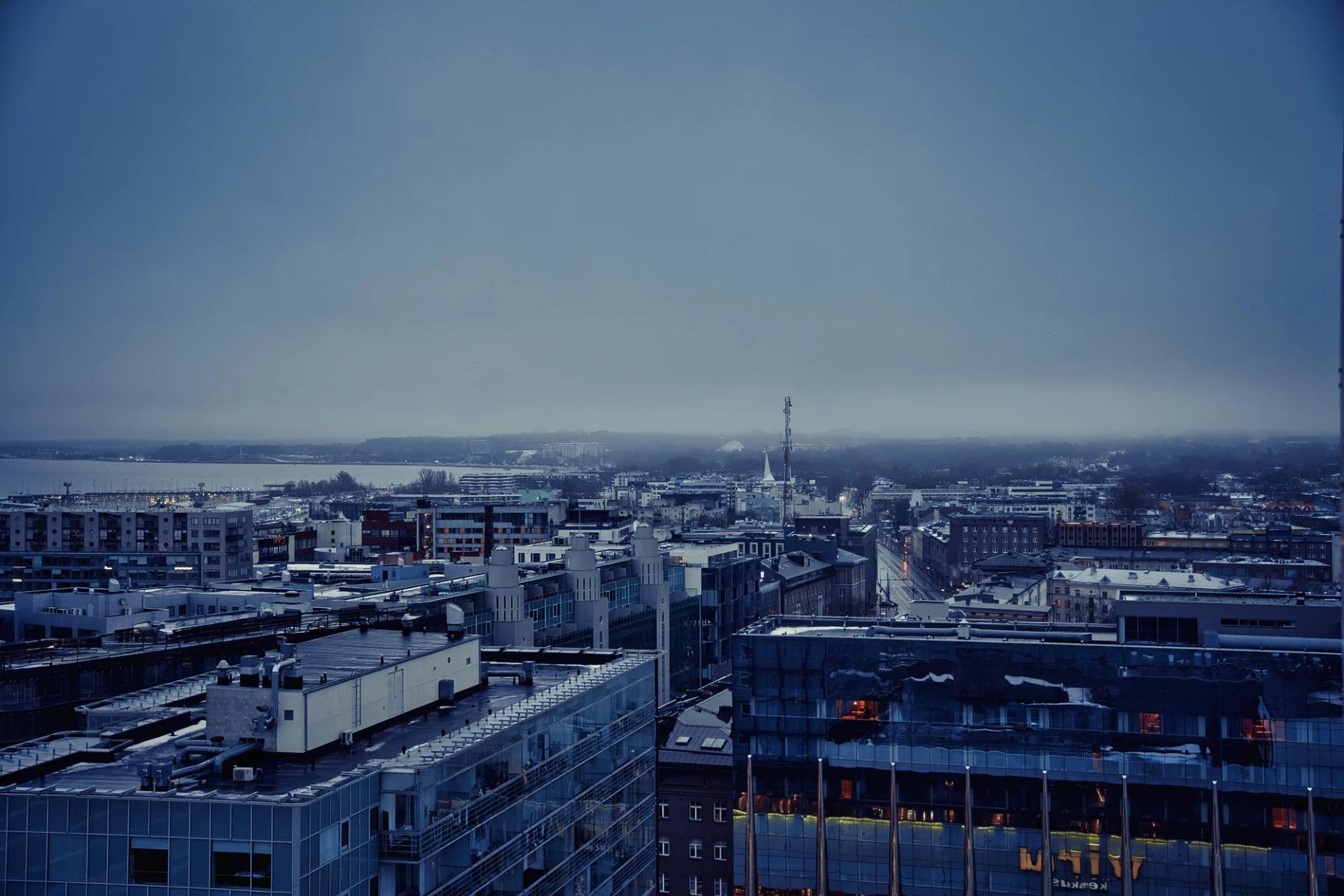 Tallinn rooftops and the Baltic waterfront beneath a dark, cool blue winter sky