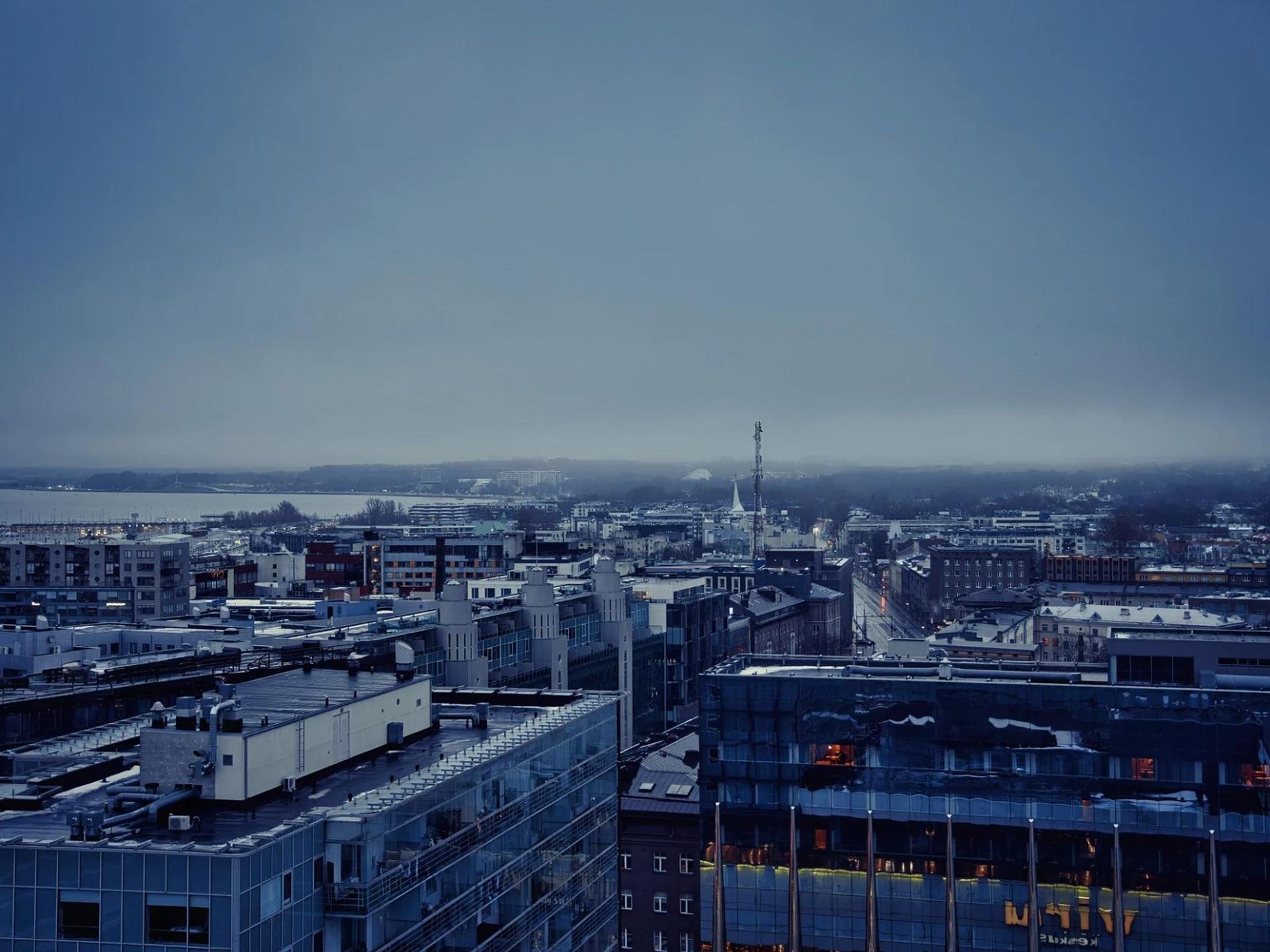 Tallinn rooftops and the Baltic waterfront beneath a dark, cool blue winter sky