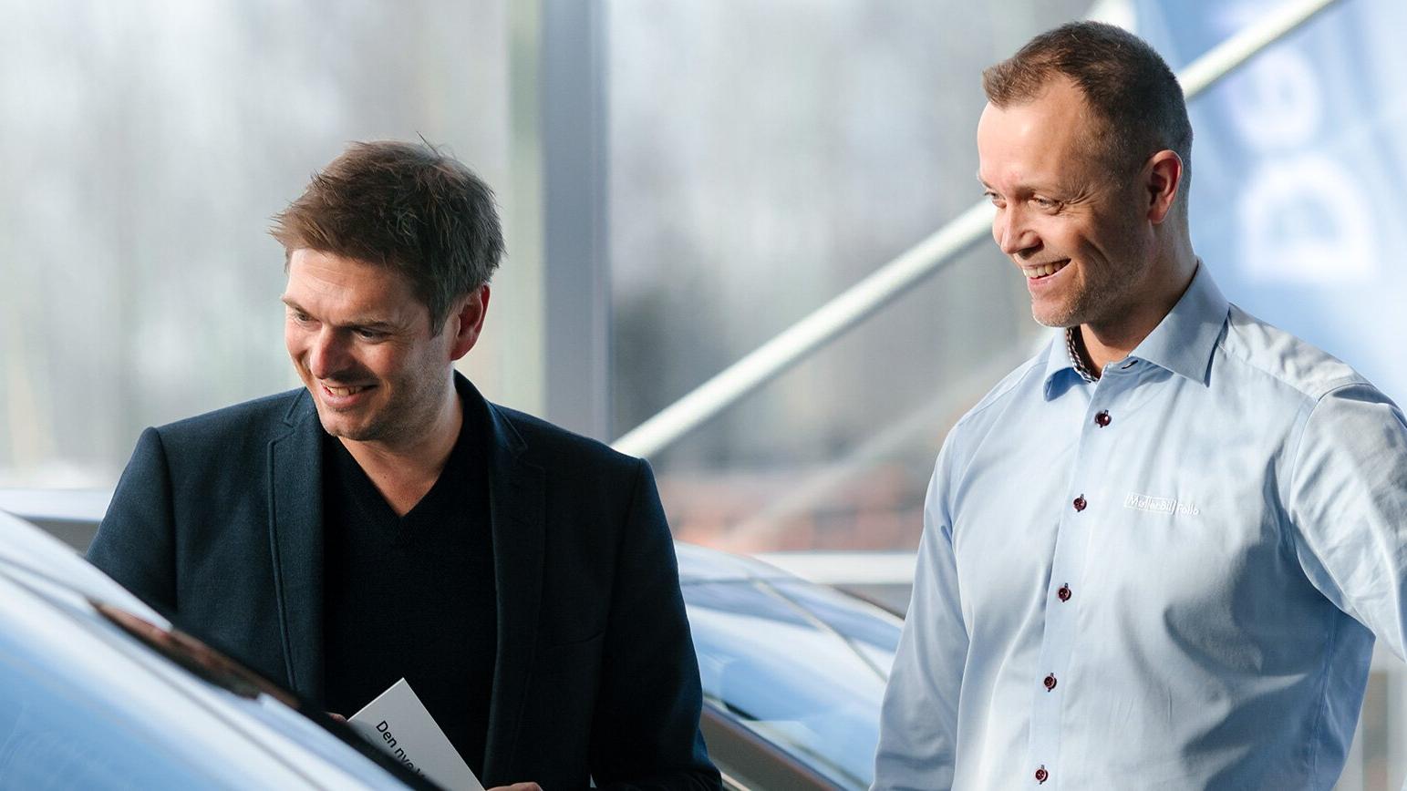 Møller Bil ansatt og kunde som kikker på ulike bilmodeller sammen i Møller Bil butikk