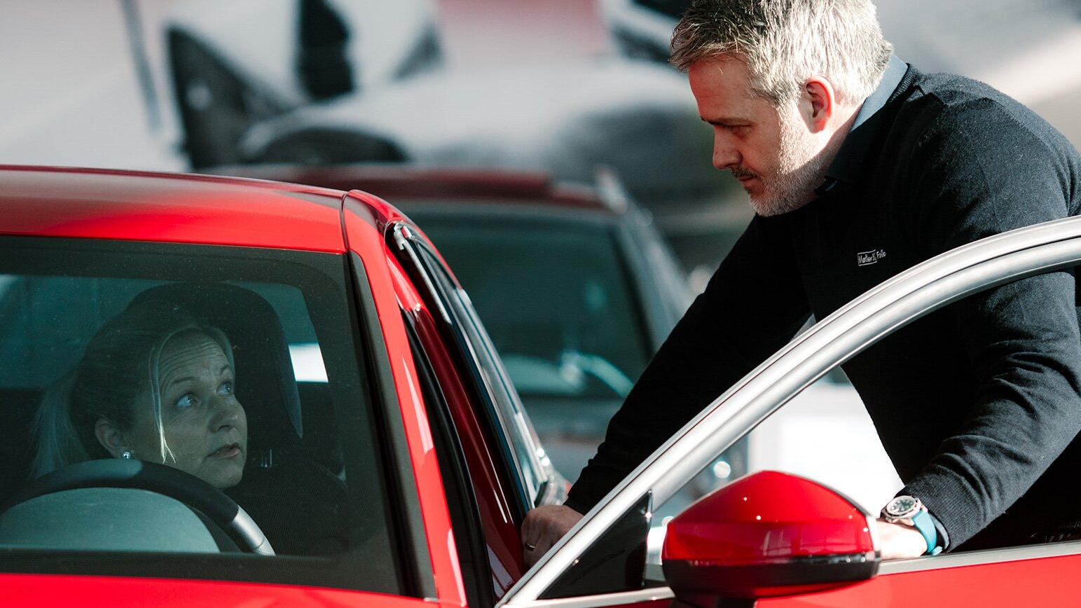 Møller Bil ansatt som prater med en kunde som sitter i bilen