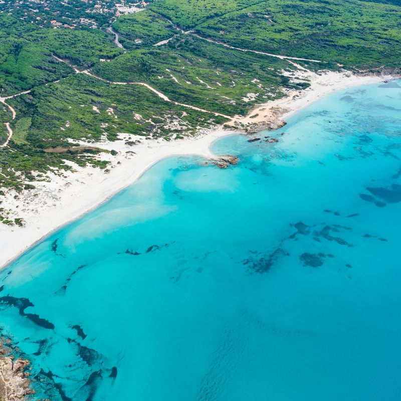 View from above, stunning aerial view of a white sand beach bathed by a turquoise water. Rena Majore, Sardinia, Italy.