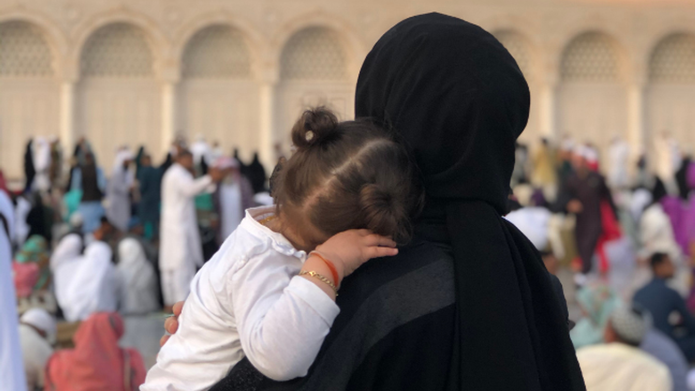 Seorang anak perempuan yang sedang mencium tangan ibunya dengan penuh kasih sayang dan rasa hormat.