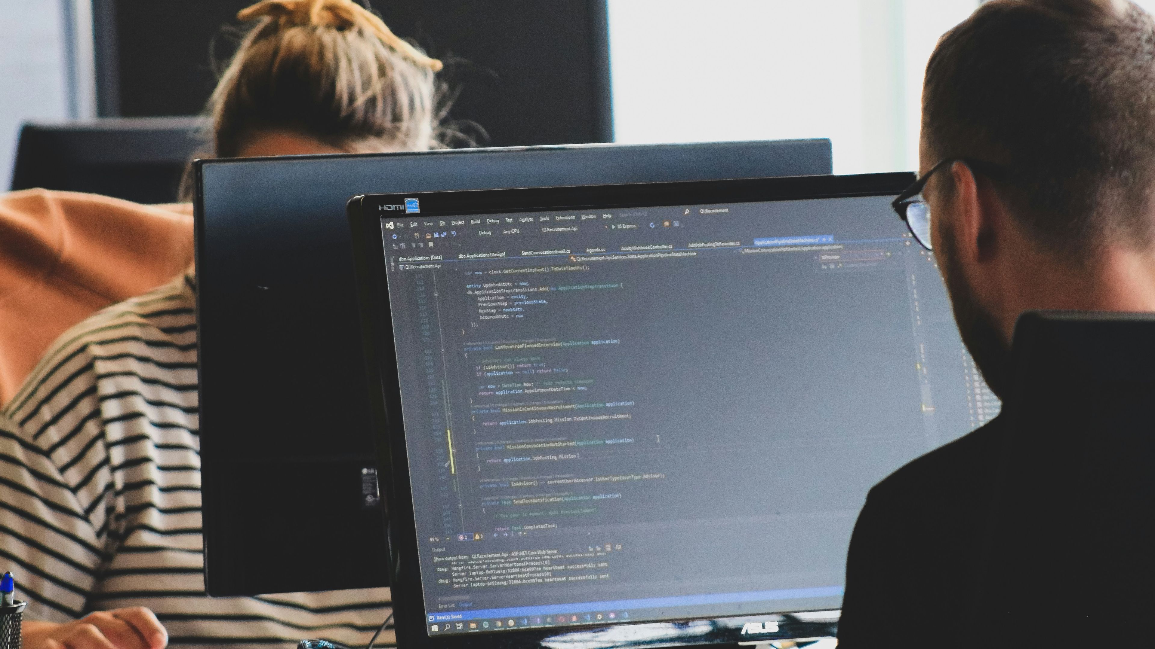 a man and a woman are sitting in front of a computer screen .