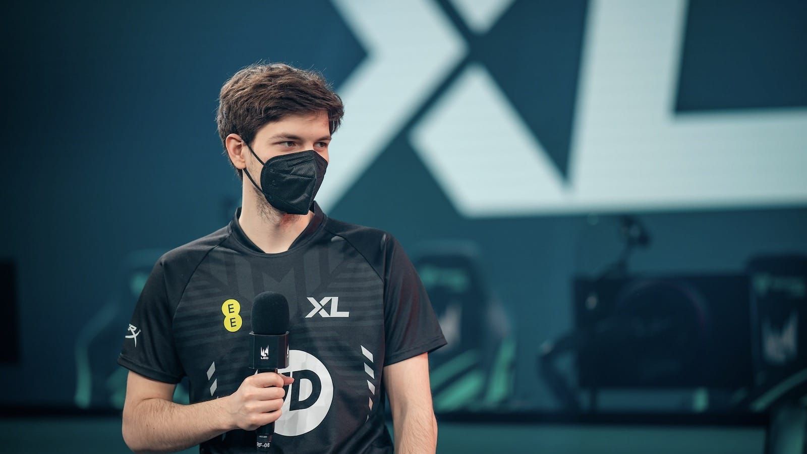 Excel Esports League of Legends player Mikyx holds a microphone onstage as he listens to an interview question