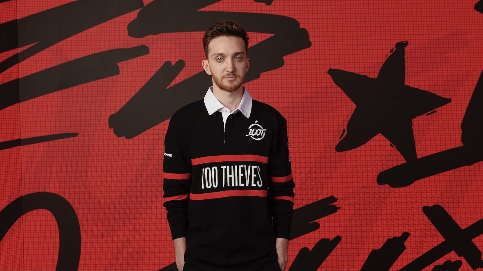 100 thieves player Closer stands in front of a red and black background wearing the team's new rugby-style 2022 jersey