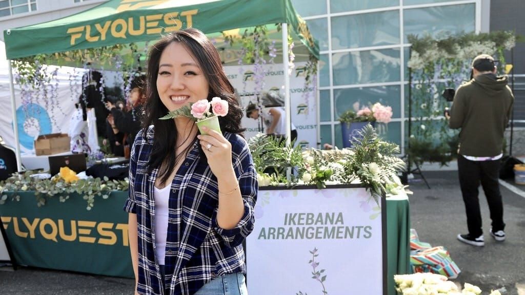 FlyQuest CEO Tricia Sugita holds flower to promote one of the org's initiatives
