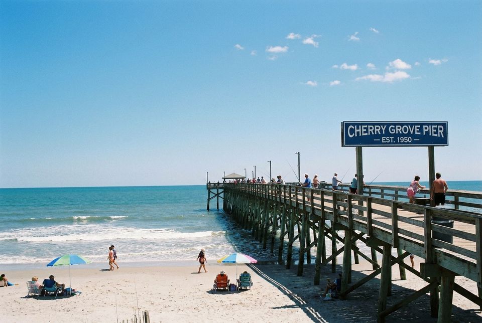 Cherry Grove fishing pier at North Myrtle Beach South Carolina with ocean waves and beachgoers