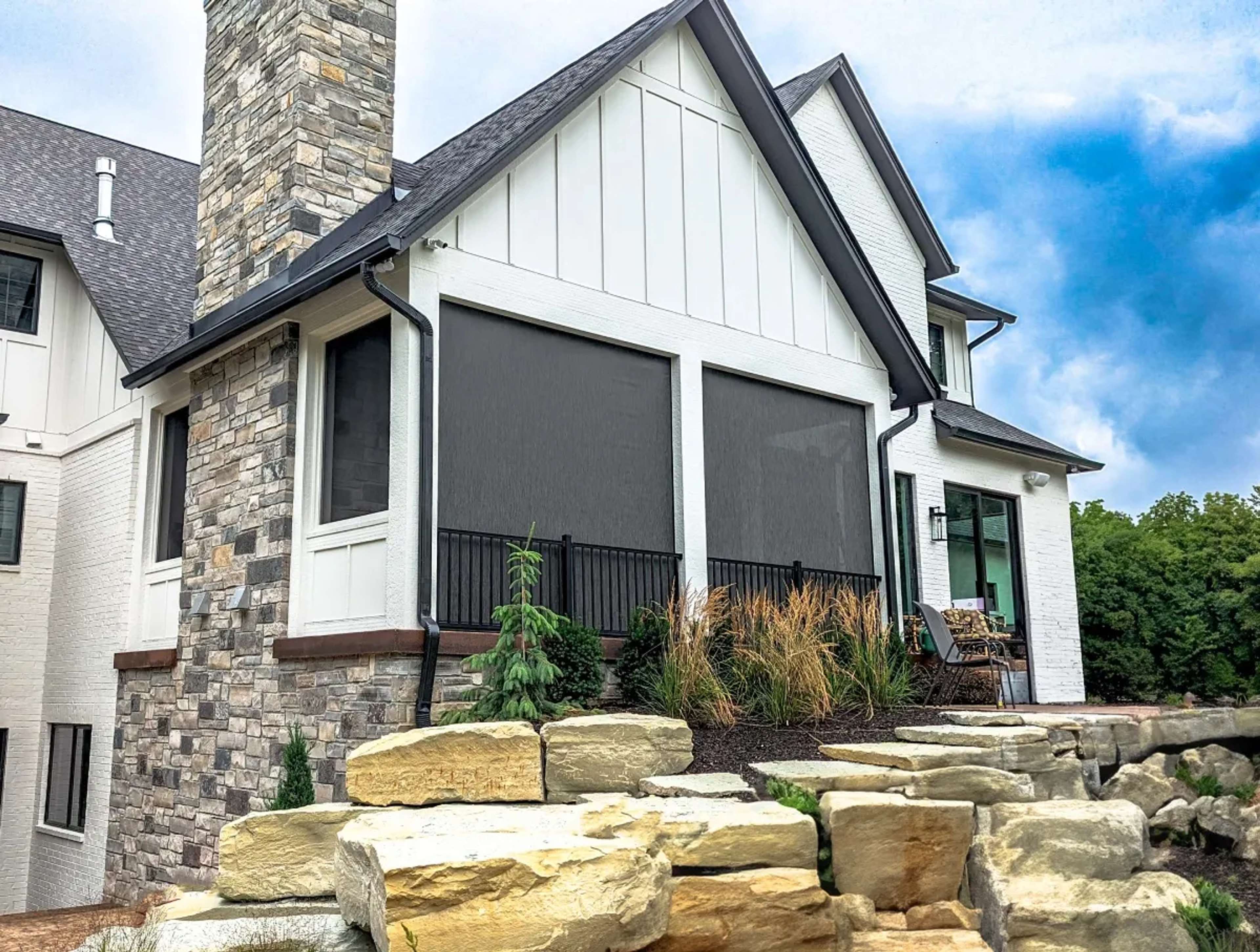 SunPro motorized screens installed on the rear porch of a two-story home, viewed from the garden.