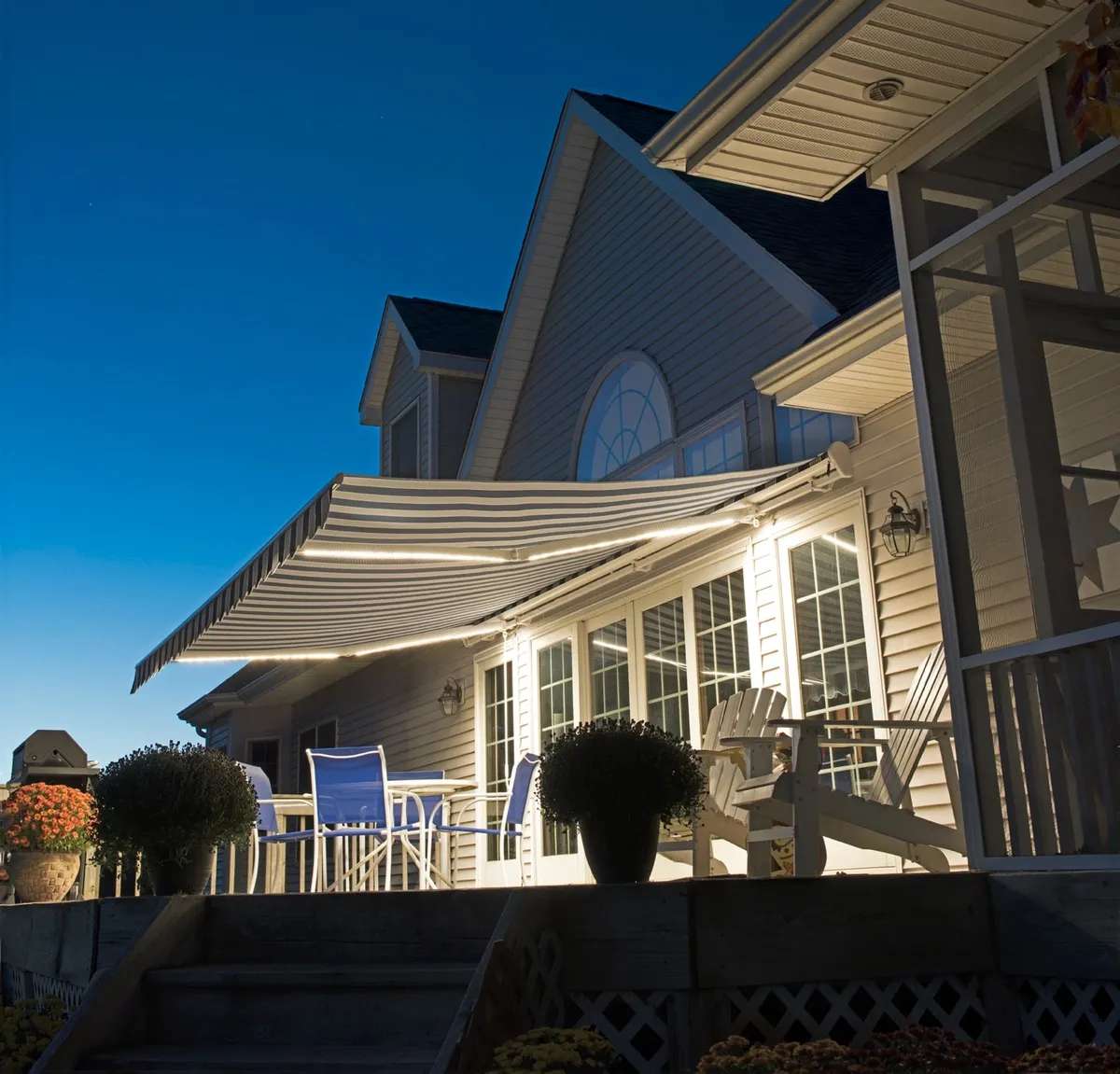 SunPro retractable awning with built-in LED arm lights glowing over a deck at dusk.