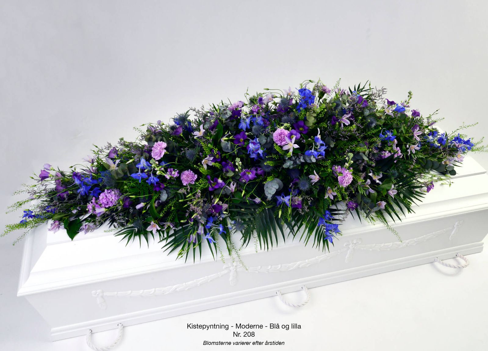 Product photography and art direction for modern casket spray with blue and purple florals