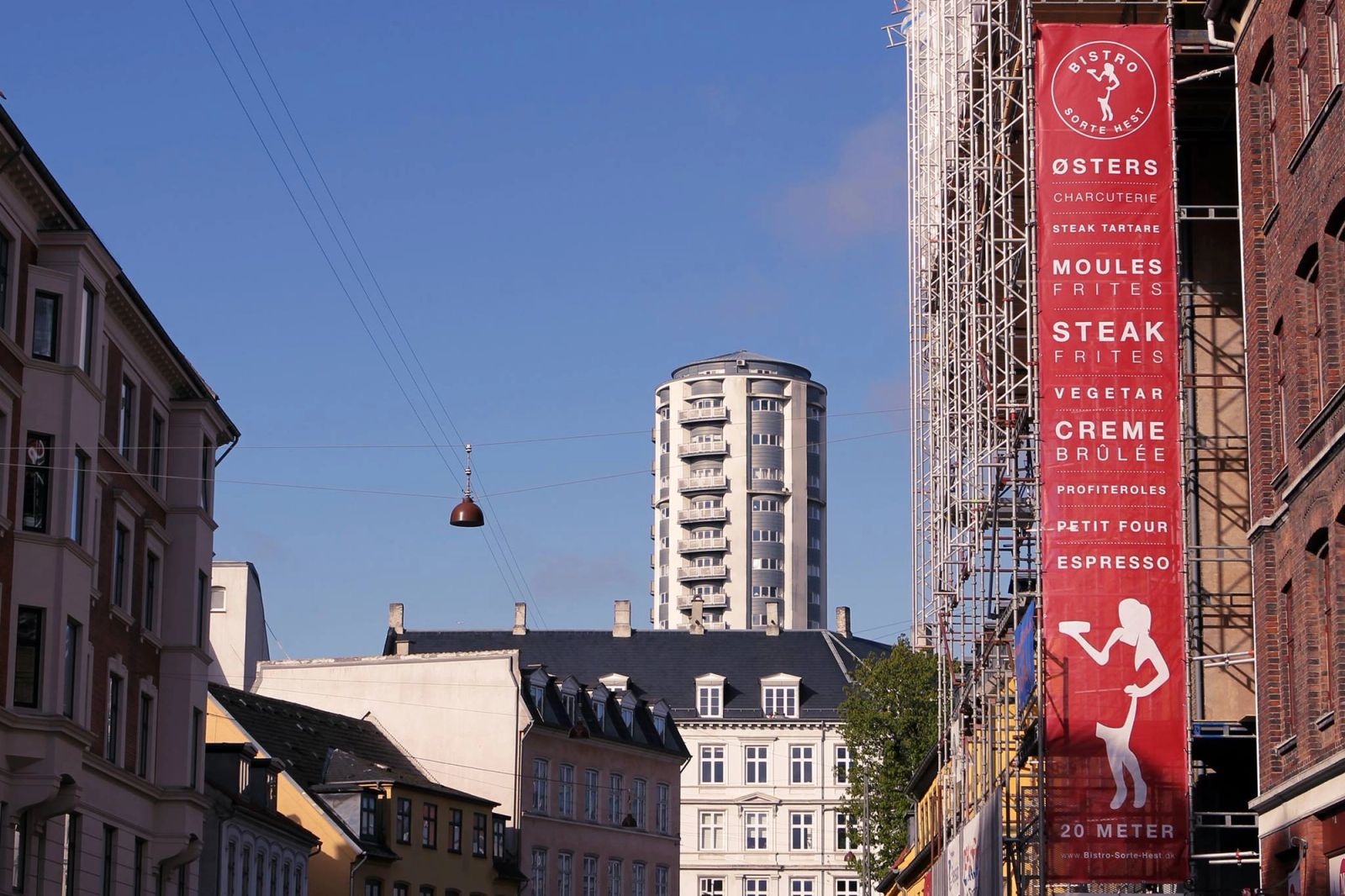Out-of-home reklame med rødt banner og typografi for fransk bistro på bykvartal i København